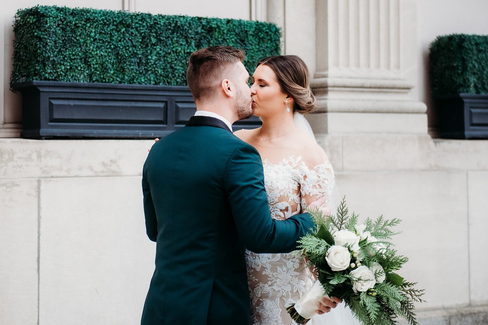 bride and groom kiss on sidewalk during first look