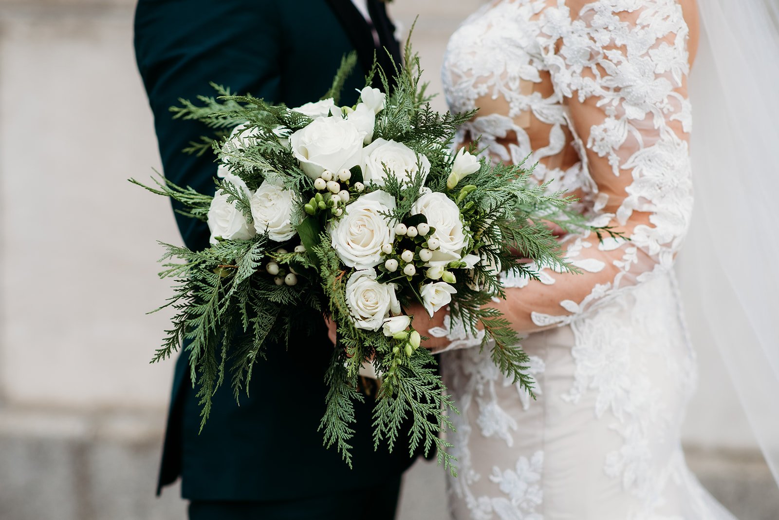 groom hugs bride to him while she holds bouquet of ivory flowers 