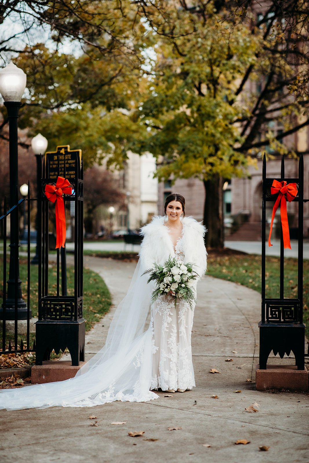 bride stands between gates in Troy NY park