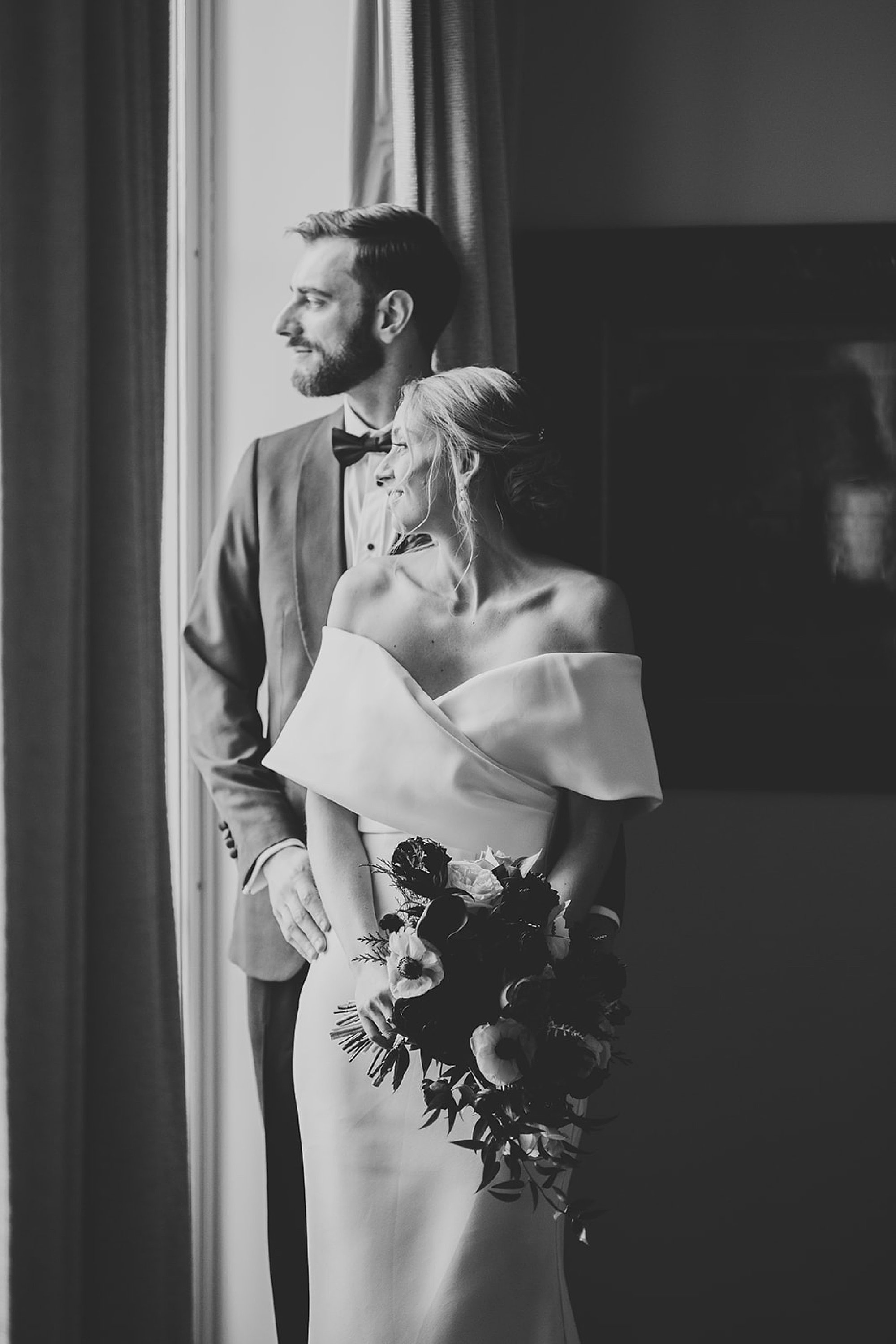 black and white portrait of groom holding bride to him in window of The Adelphi Hotel