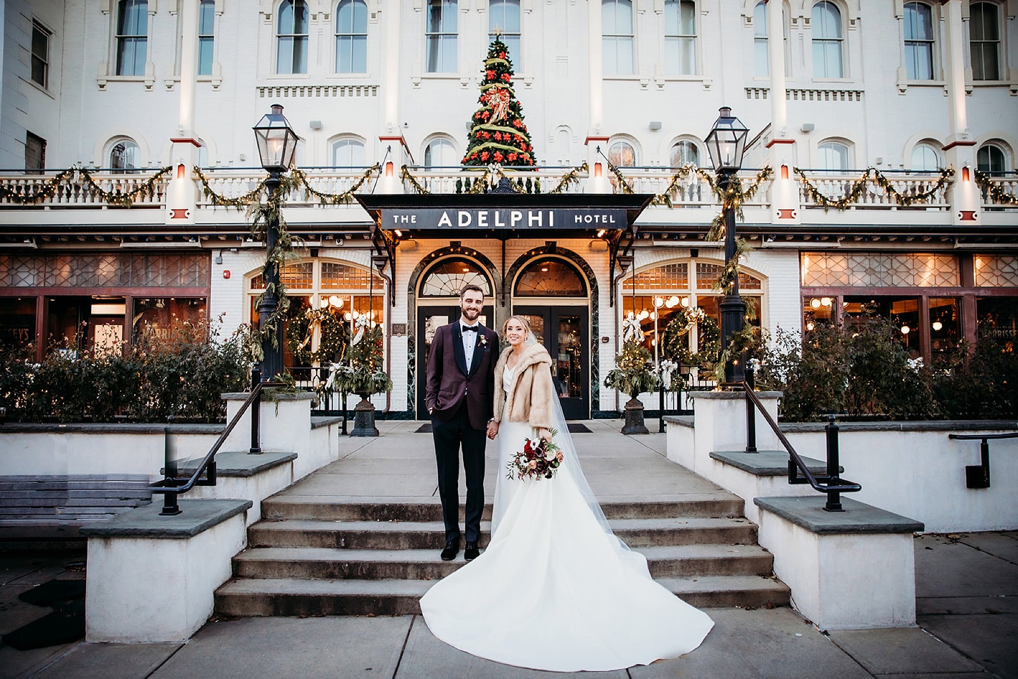 bride and groom stand on steps outside The Adelphi Hotel