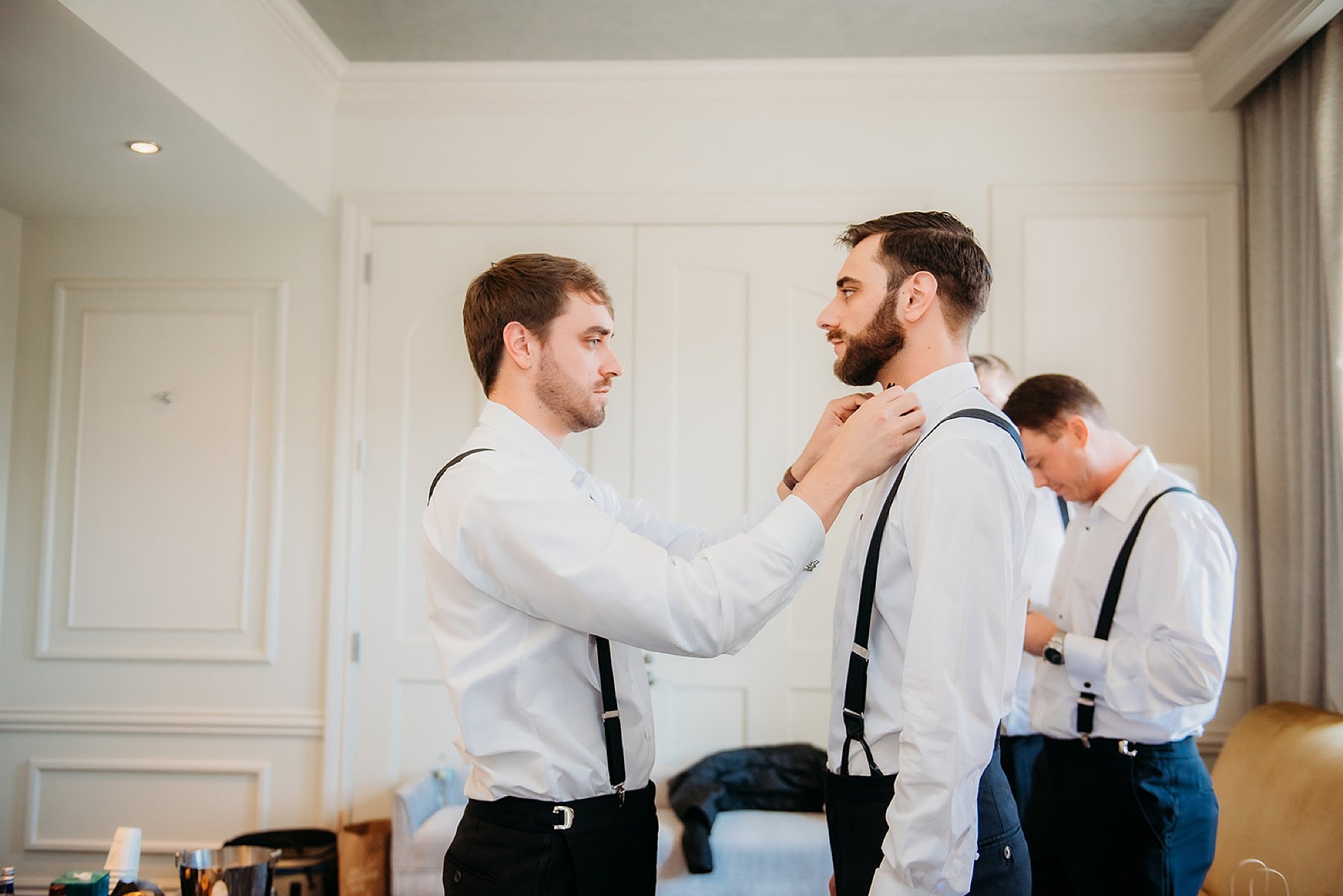 best man helps groom adjust tie
