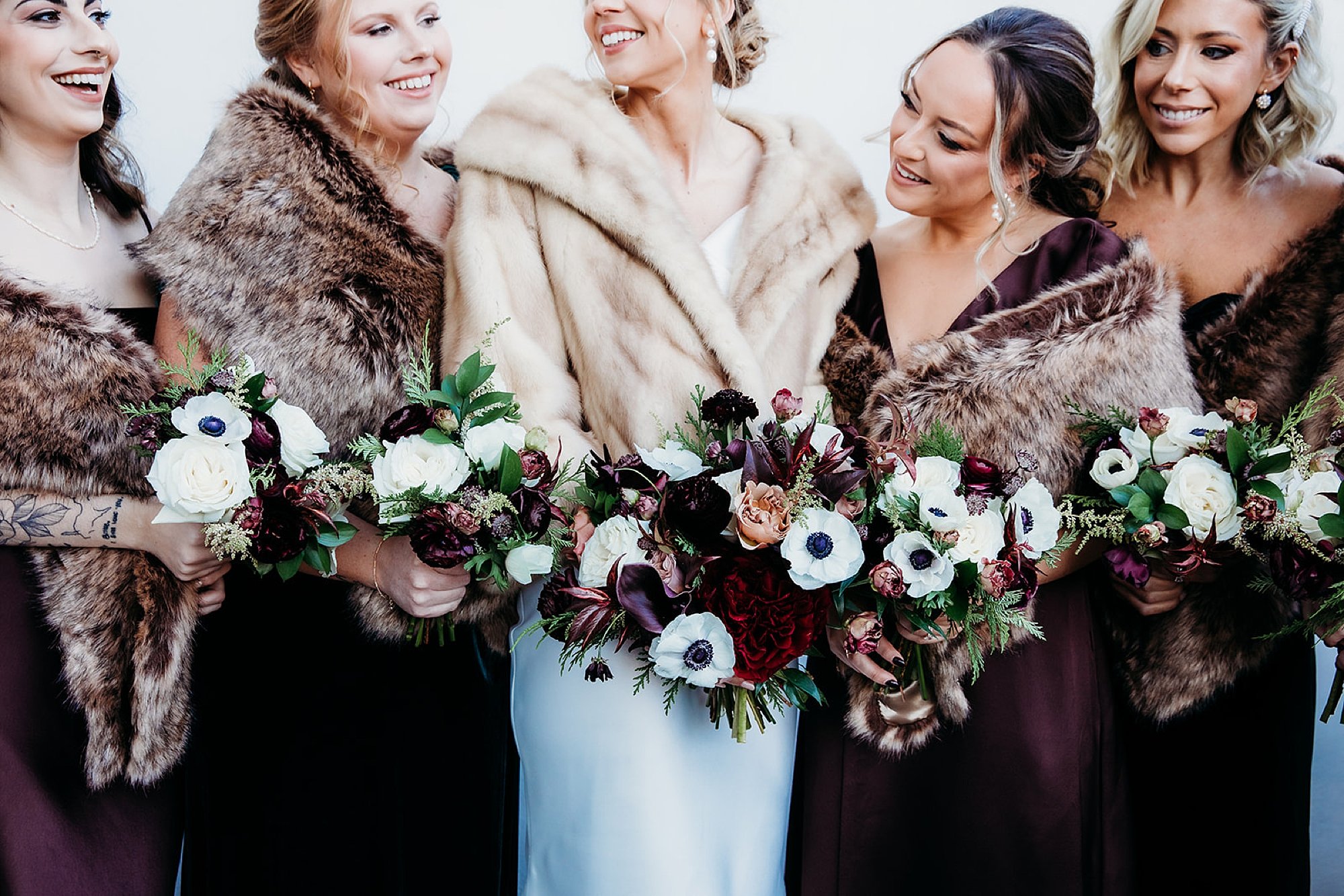 bride poses with bridesmaids in furs outside The Adelphi Hotel