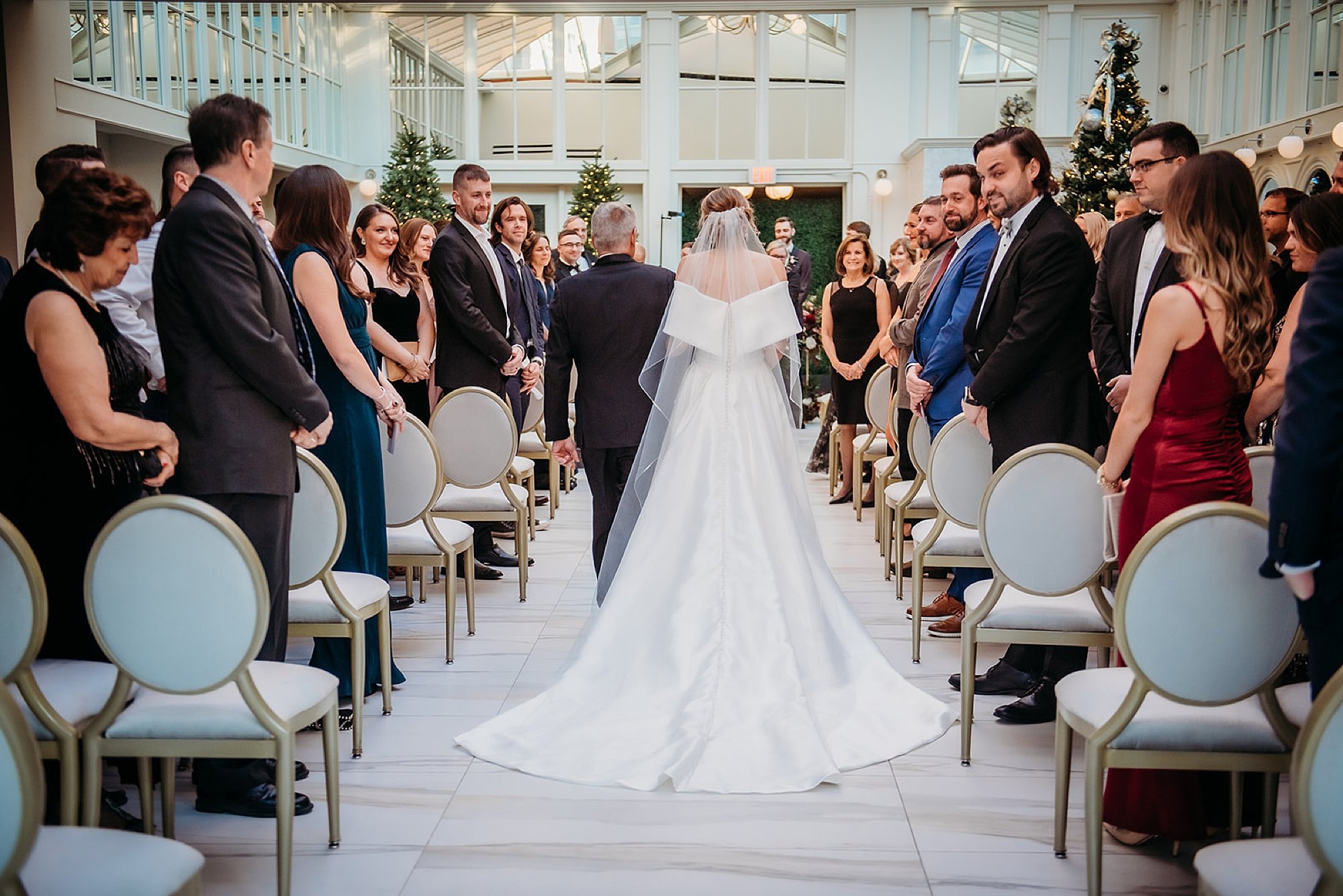 bride walks down aisle with father for wedding ceremony in atrium at The Adelphi Hotel in Saratoga Springs NY