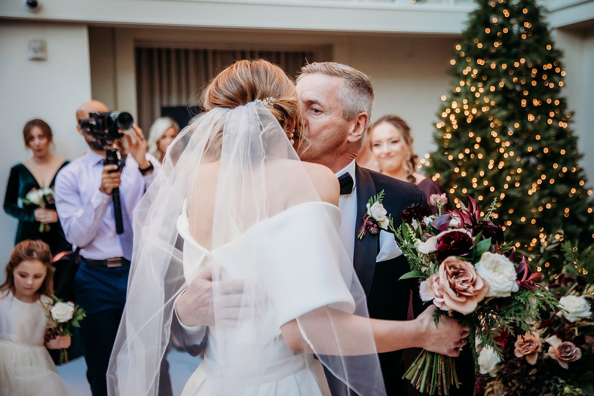 father kisses bride's cheek at end of aisle