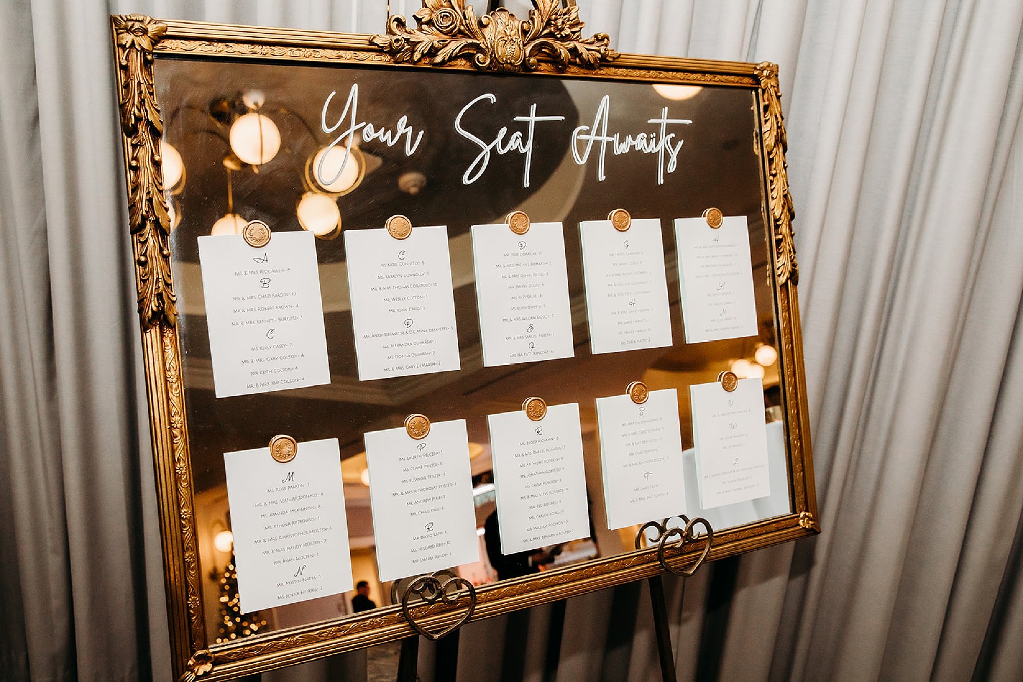 seating chart on gold mirror with calligraphy 