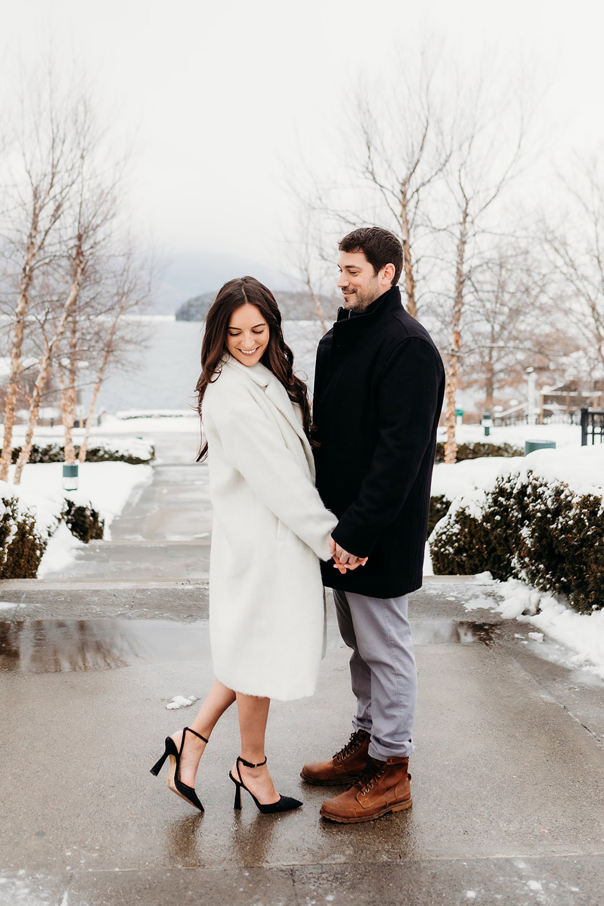 man holds woman's hands while she pops foot and looks over shoulder 