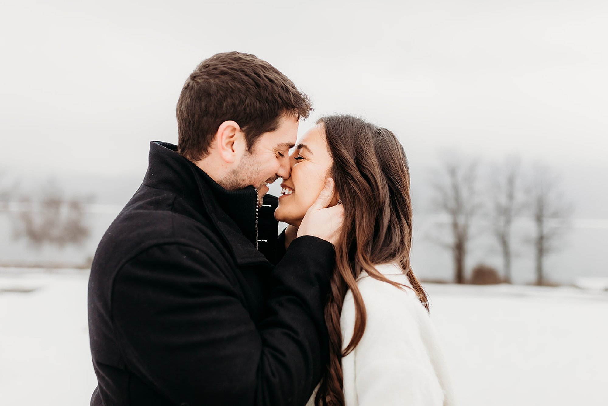 man leans to kiss fiancee during engagement portraits on Lake George 