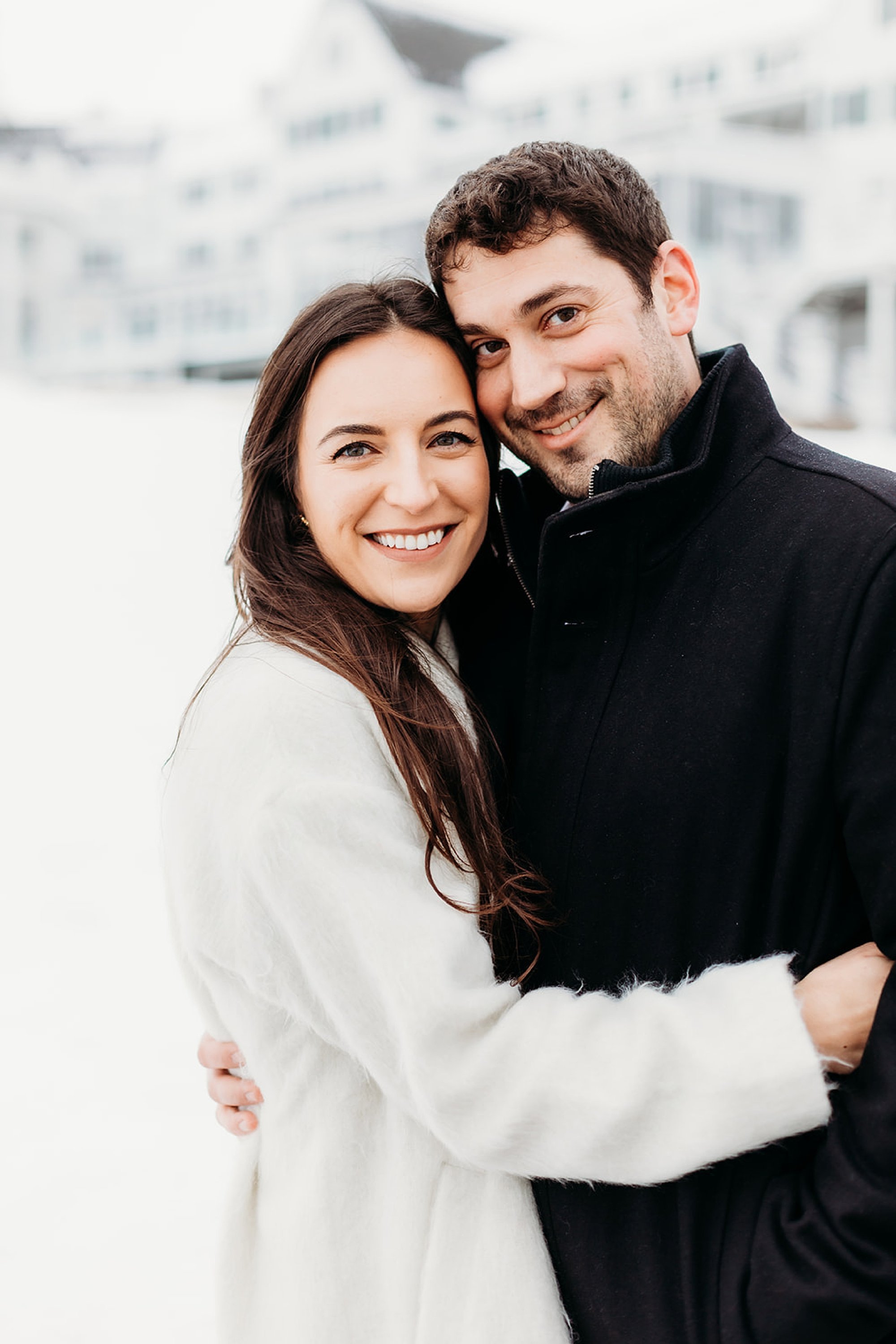 engaged couple stands leaning heads together in the snow at The Sagamore Resort