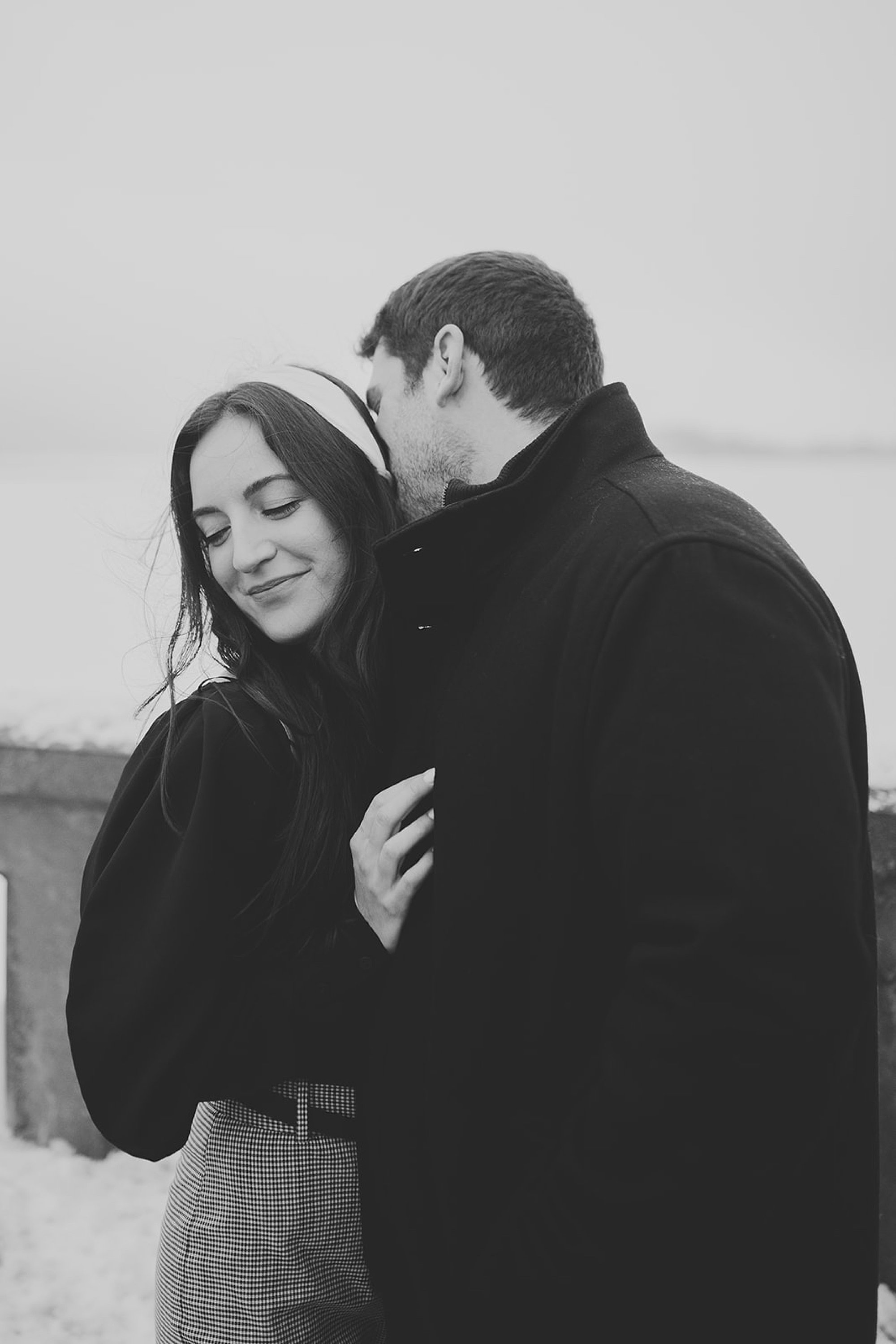 man leans to kiss woman's neck in the snow