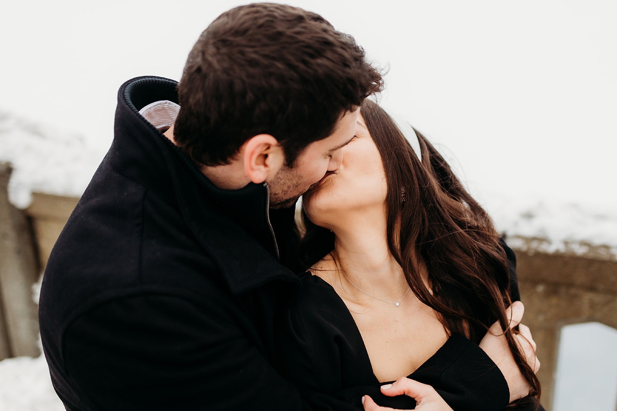 woman leans up to kiss man in the snow