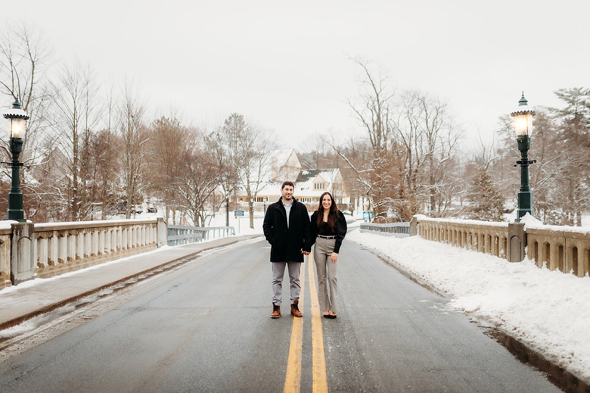 couple walks on street near Lake George in the snow