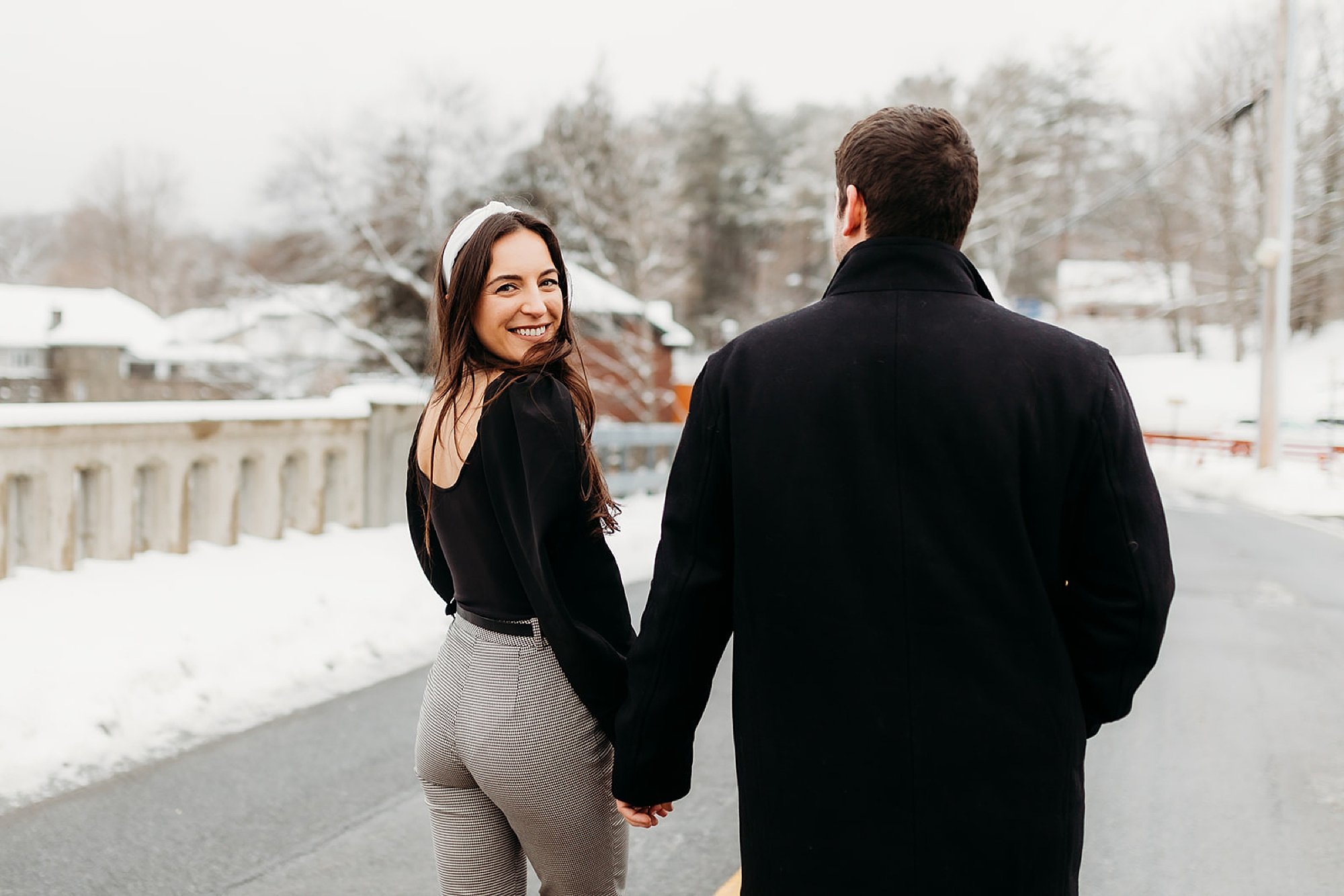 couple holds hands while woman looks over shoulder in pant outfit