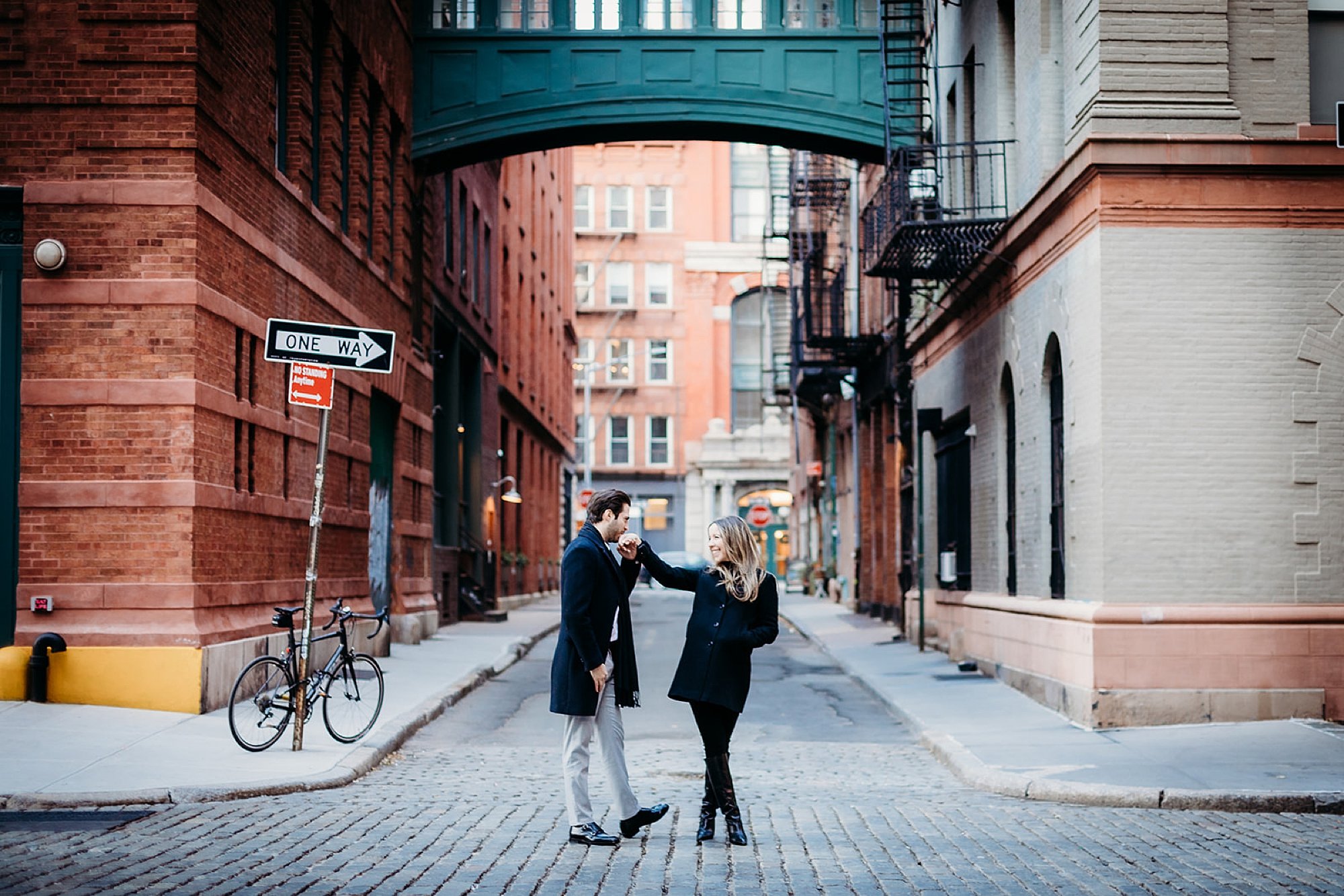 groom kisses woman's hand on cobblestone street in Tribeca NY