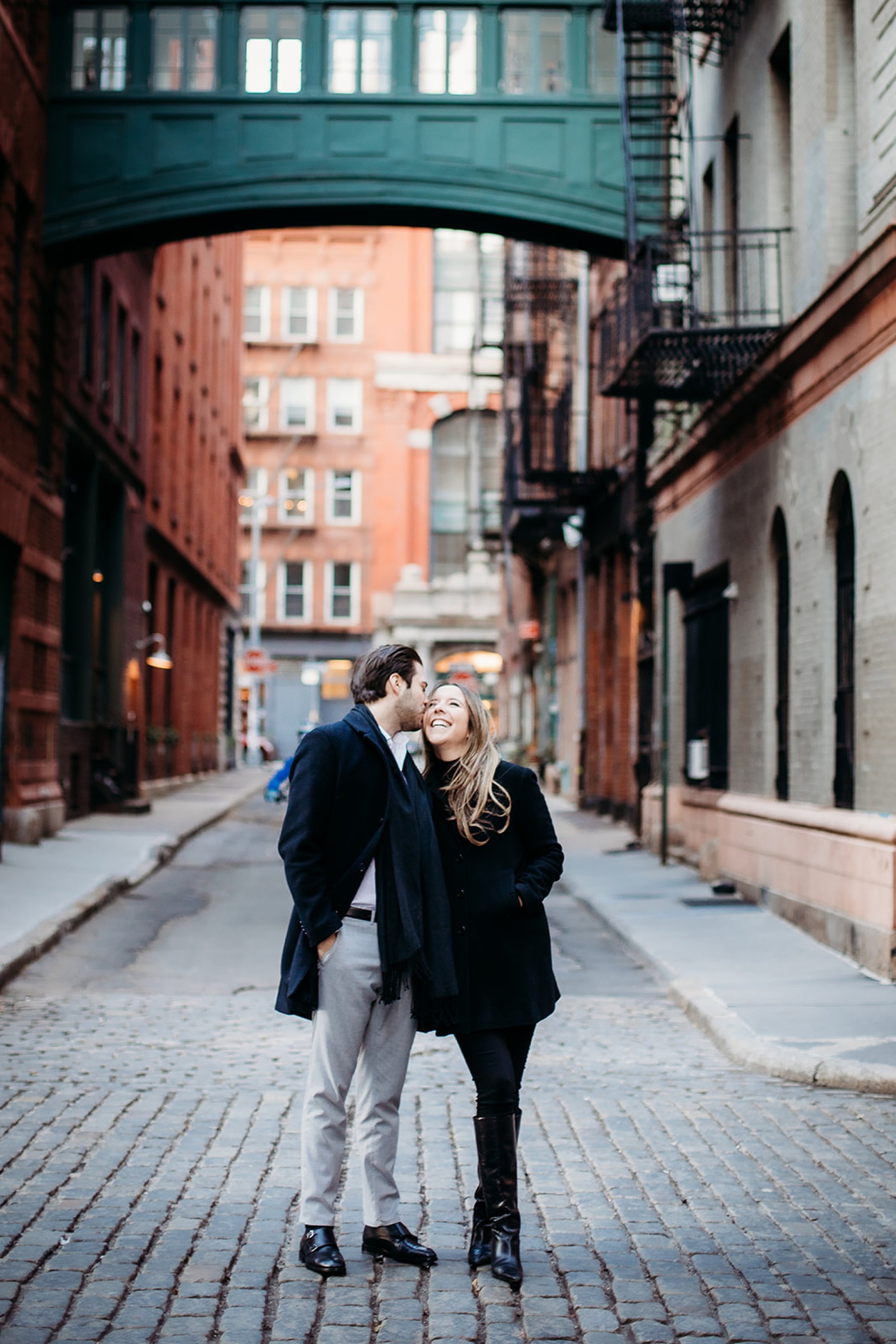 man kisses woman's forehead standing on stone streets in Tribeca NY