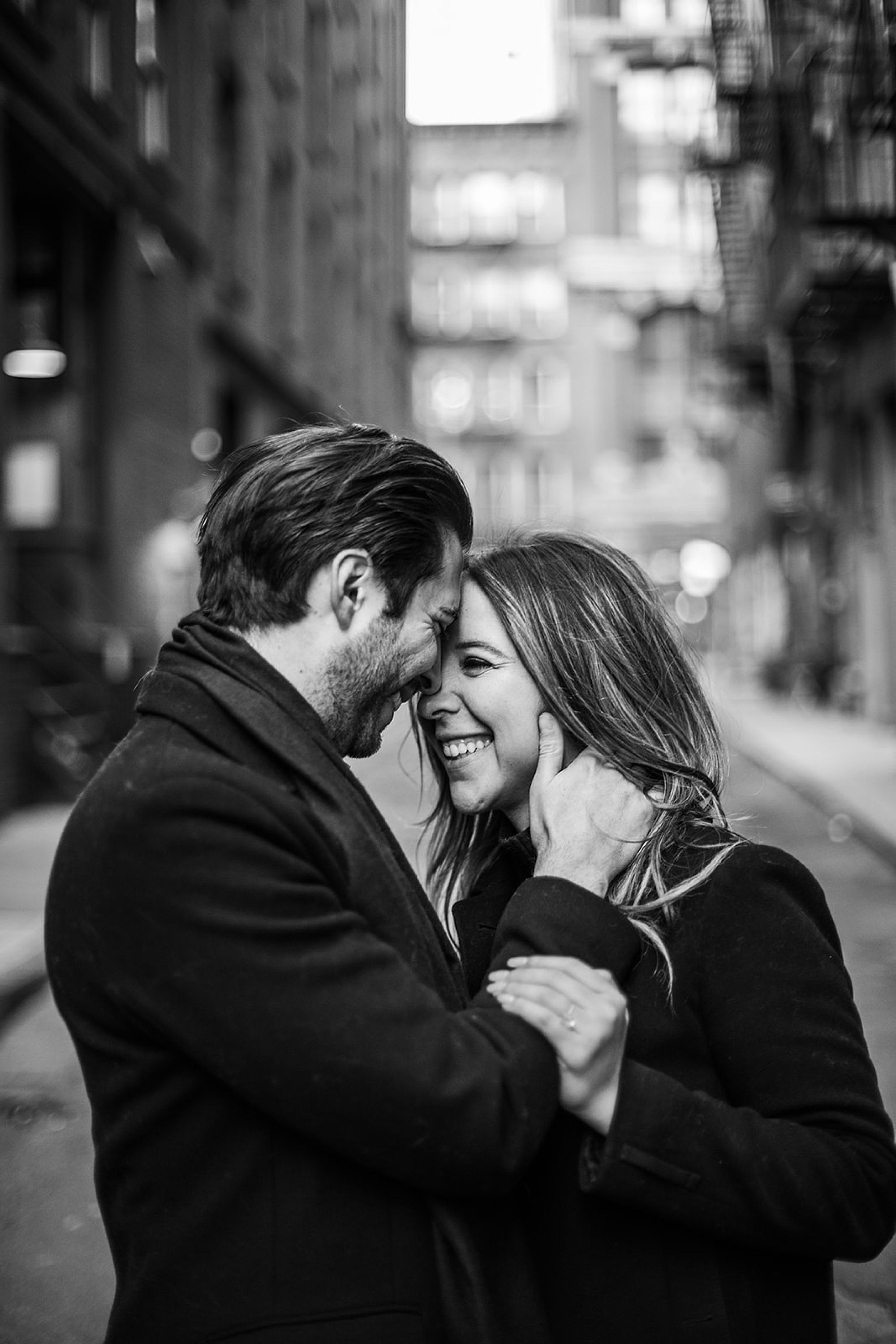 black and white portrait of couple laughing with foreheads touching 