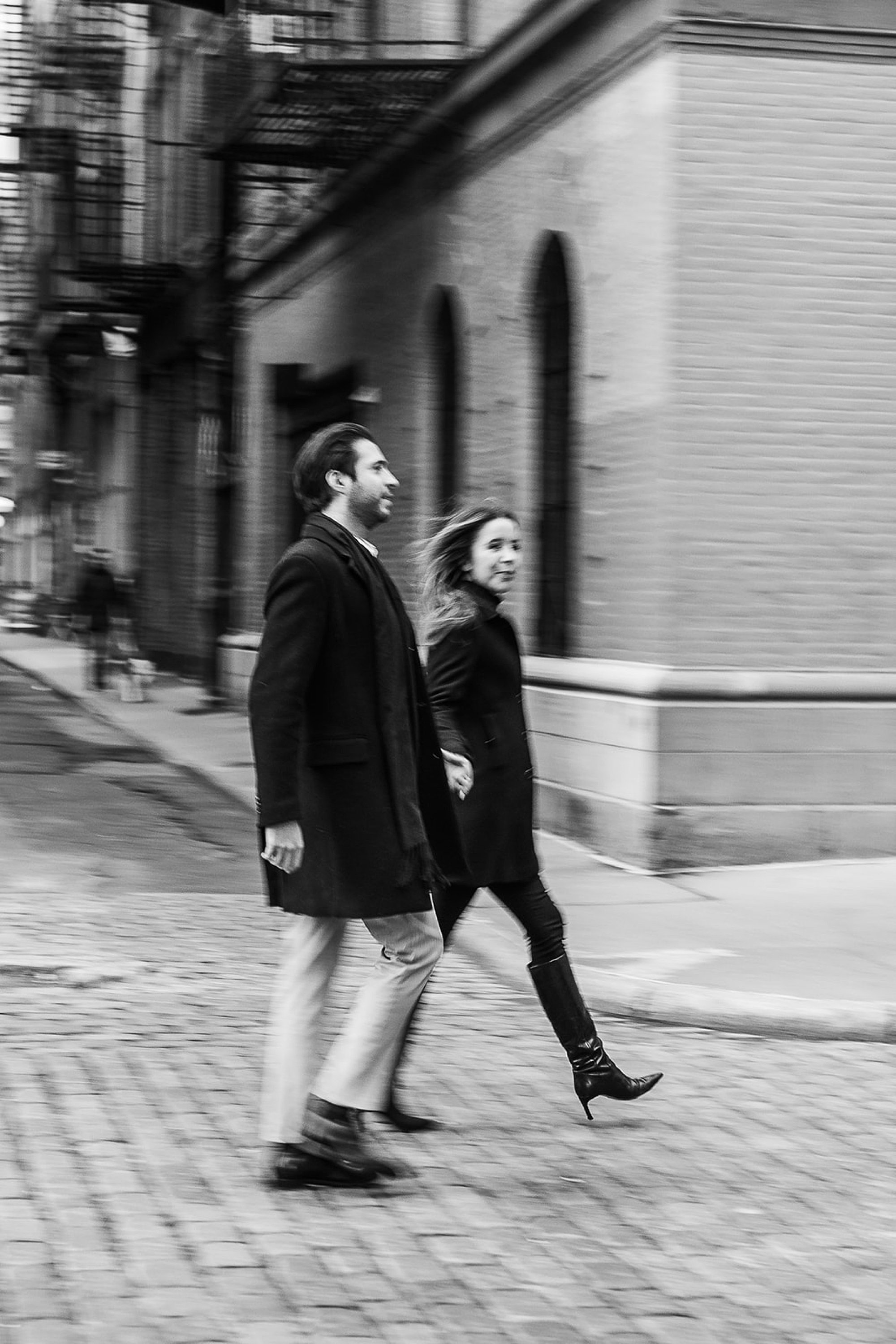 engaged couple holds hands walking around corner in Tribeca NY