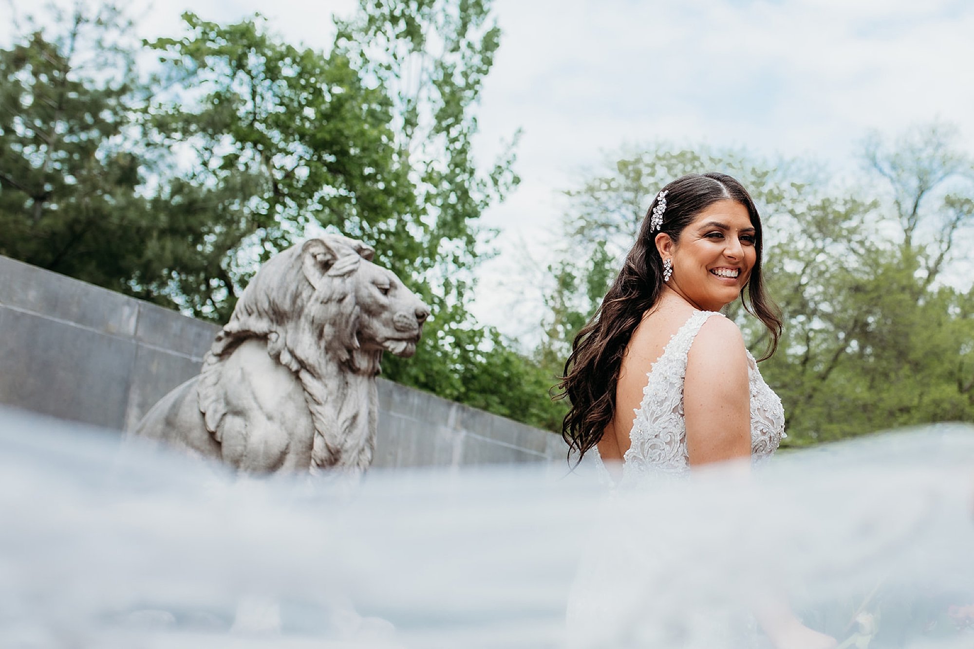 bride smiles while veil floats around her in the Bronx Zoo