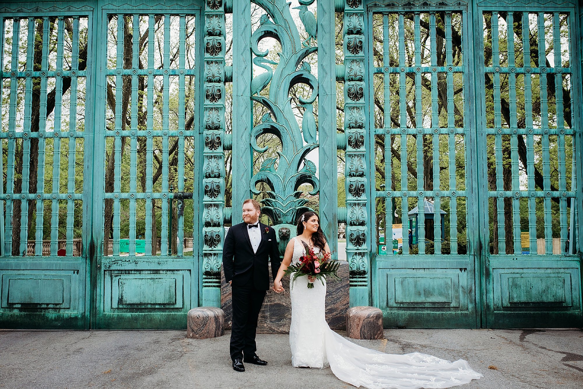 newlyweds hold hands looking away from each other outside the Rainey Memorial Garden at the Bronx Zoo