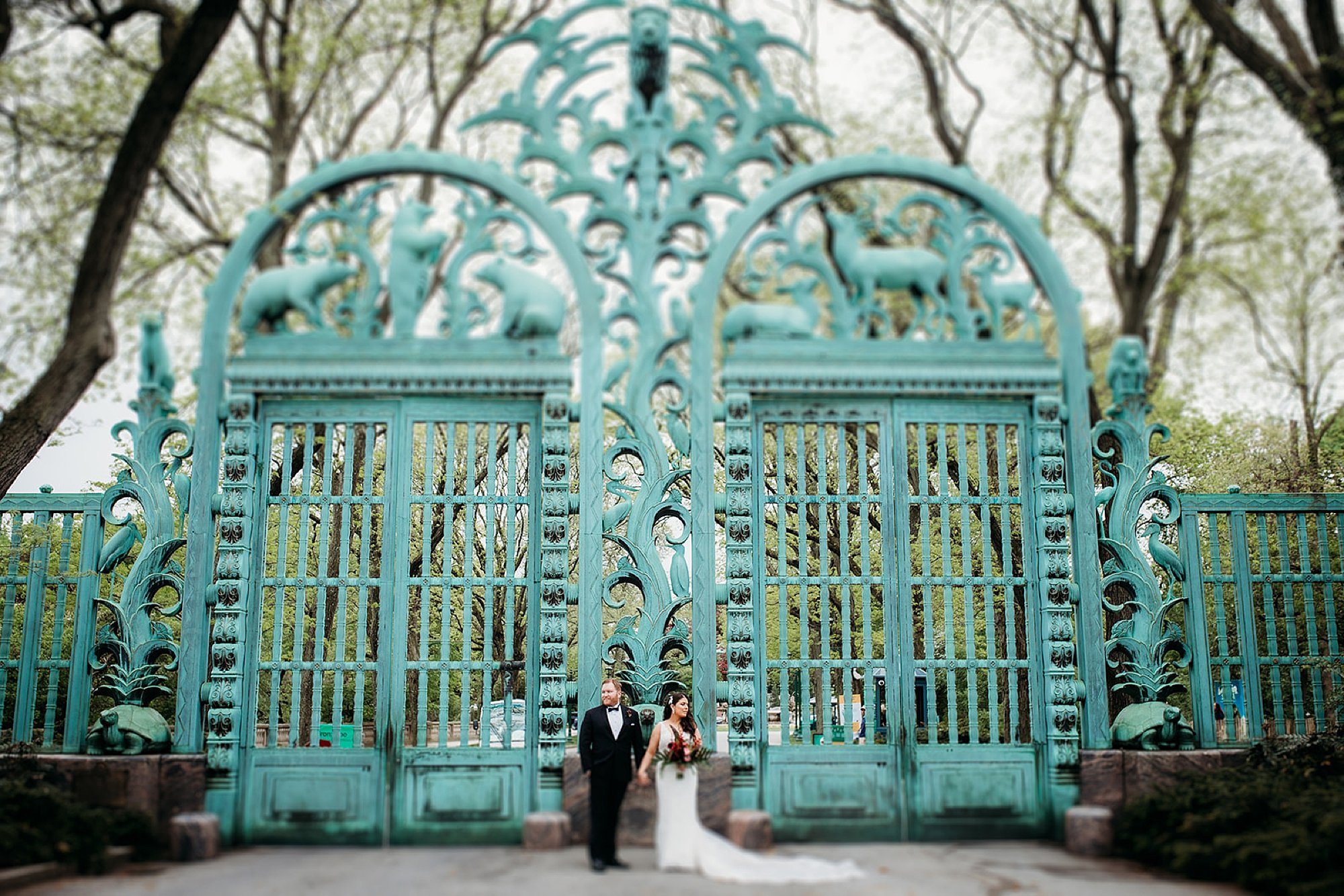 husband and wife hold hands looking away from each other by blue Rainey Memorial Garden at the Bronx Zoo