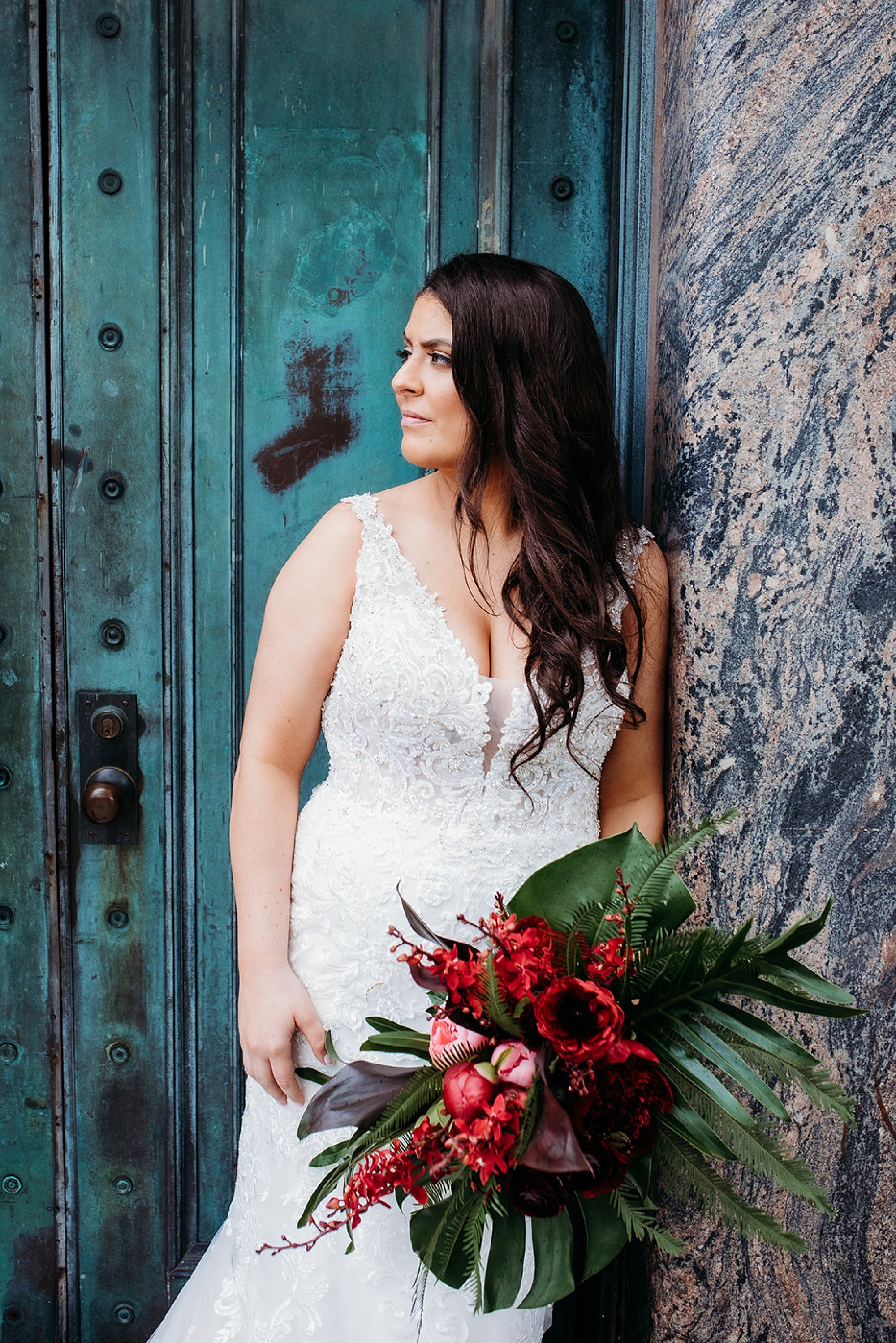 bride leans against brown wall in front of teal door at the Bronx Zoo