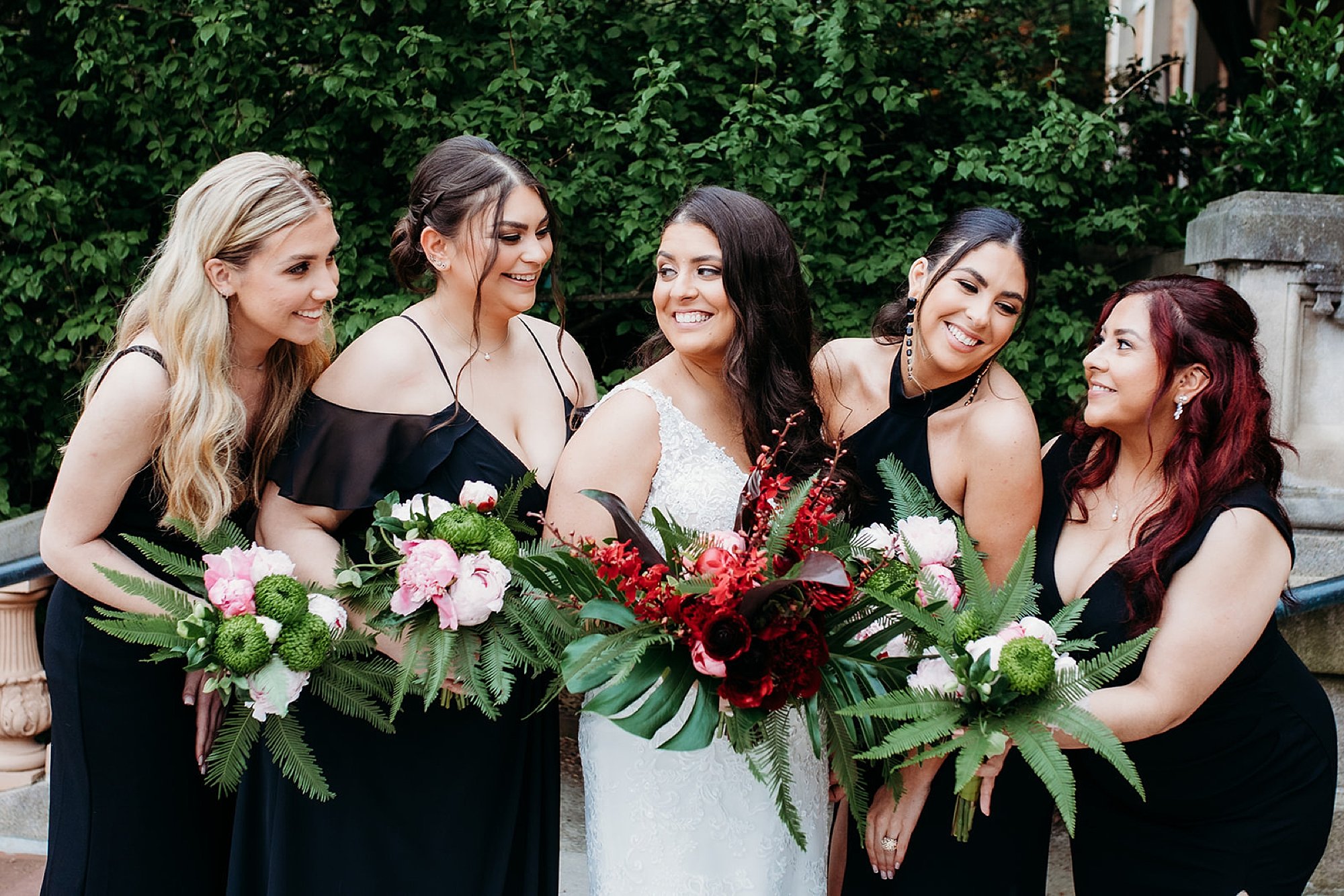 bride smiles with bridesmaids in black dresses holding tropical bouquets at the Bronx Zoo