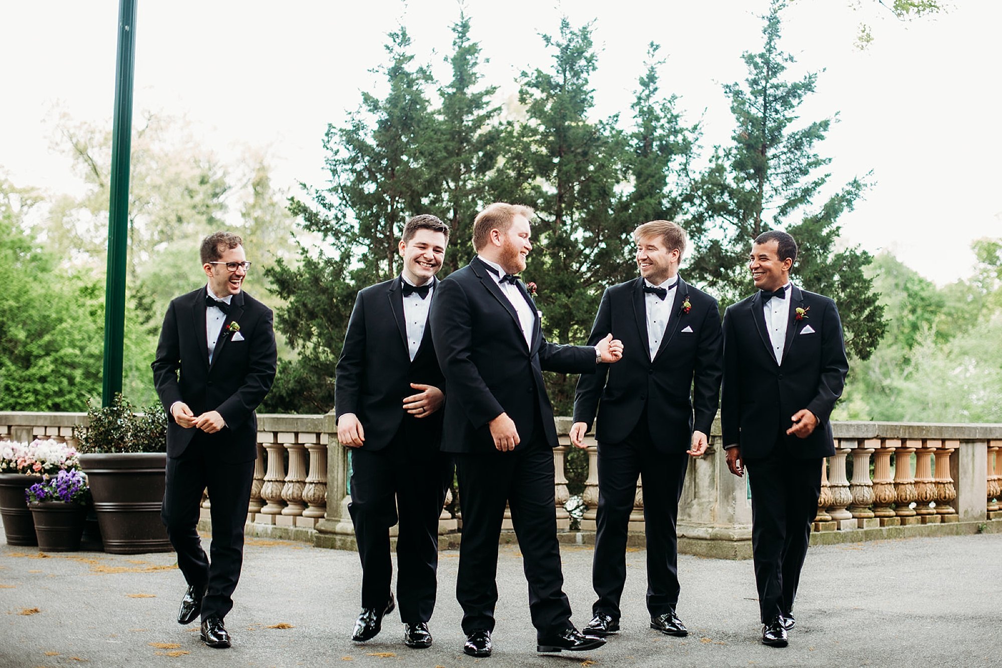 groom talks with groomsmen in black suits at the Bronx Zoo