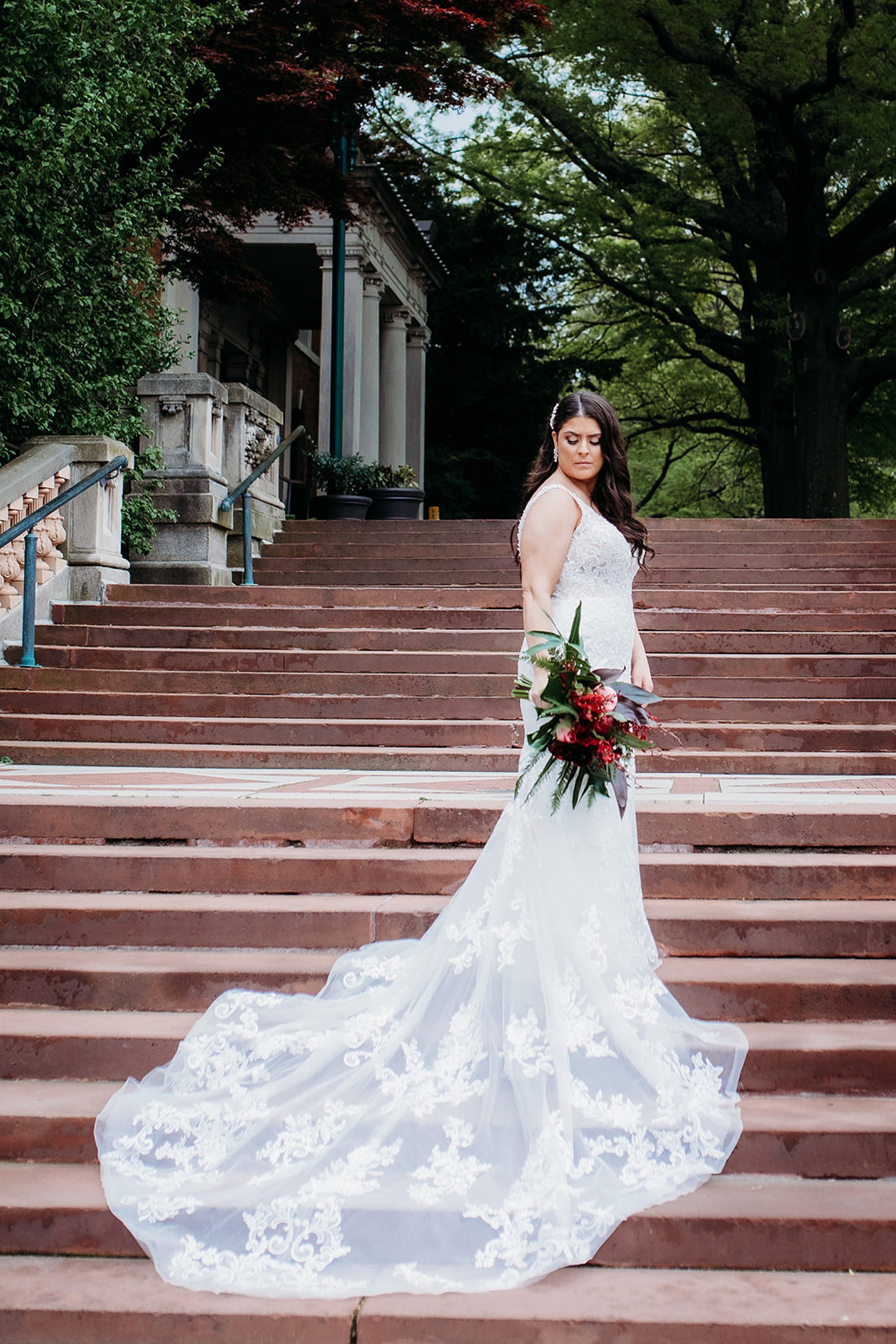 bride stands on steps at The Bronx Zoo with dress behind her 