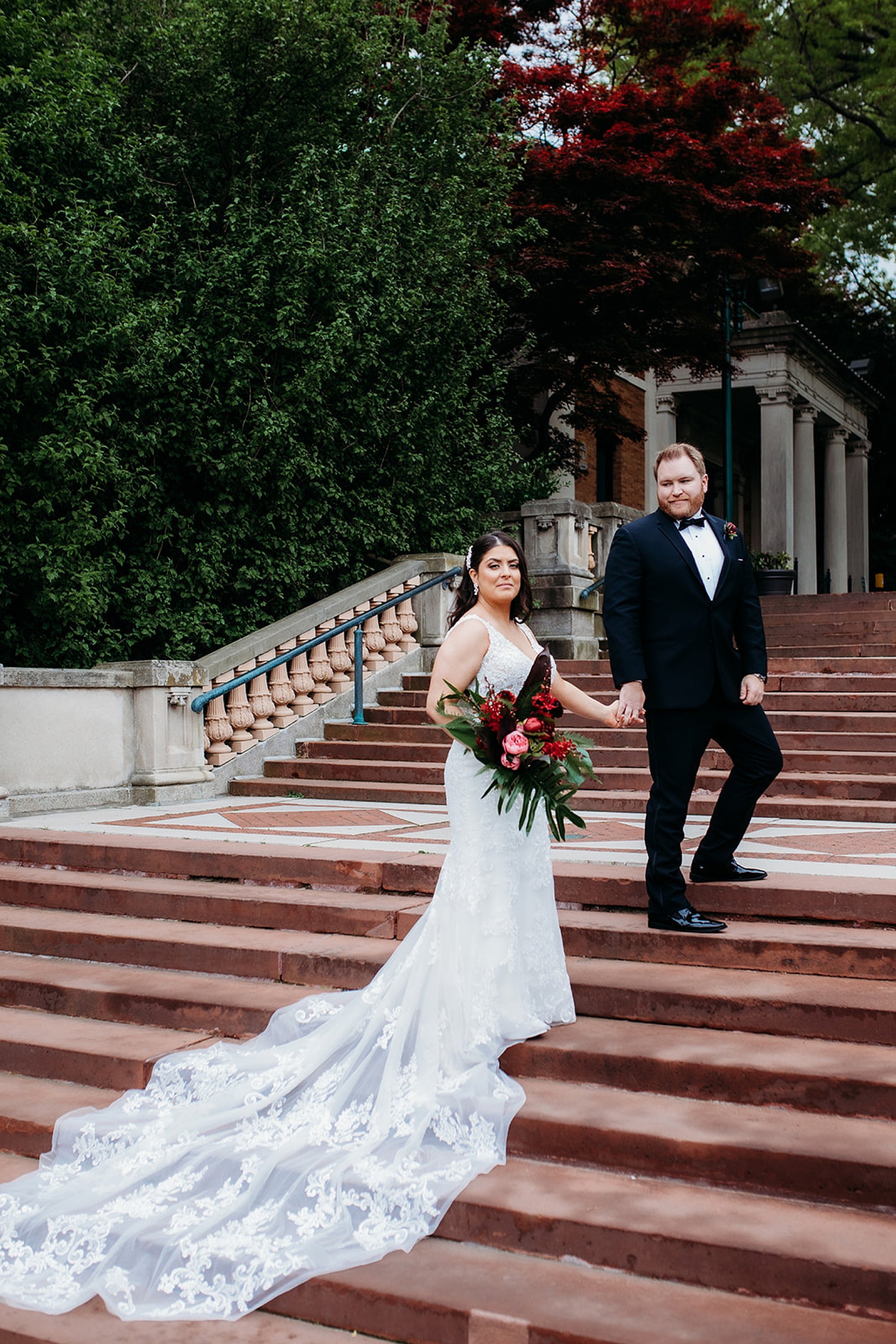 groom walks up steps at the Bronx Zoo with bride walking behind him 