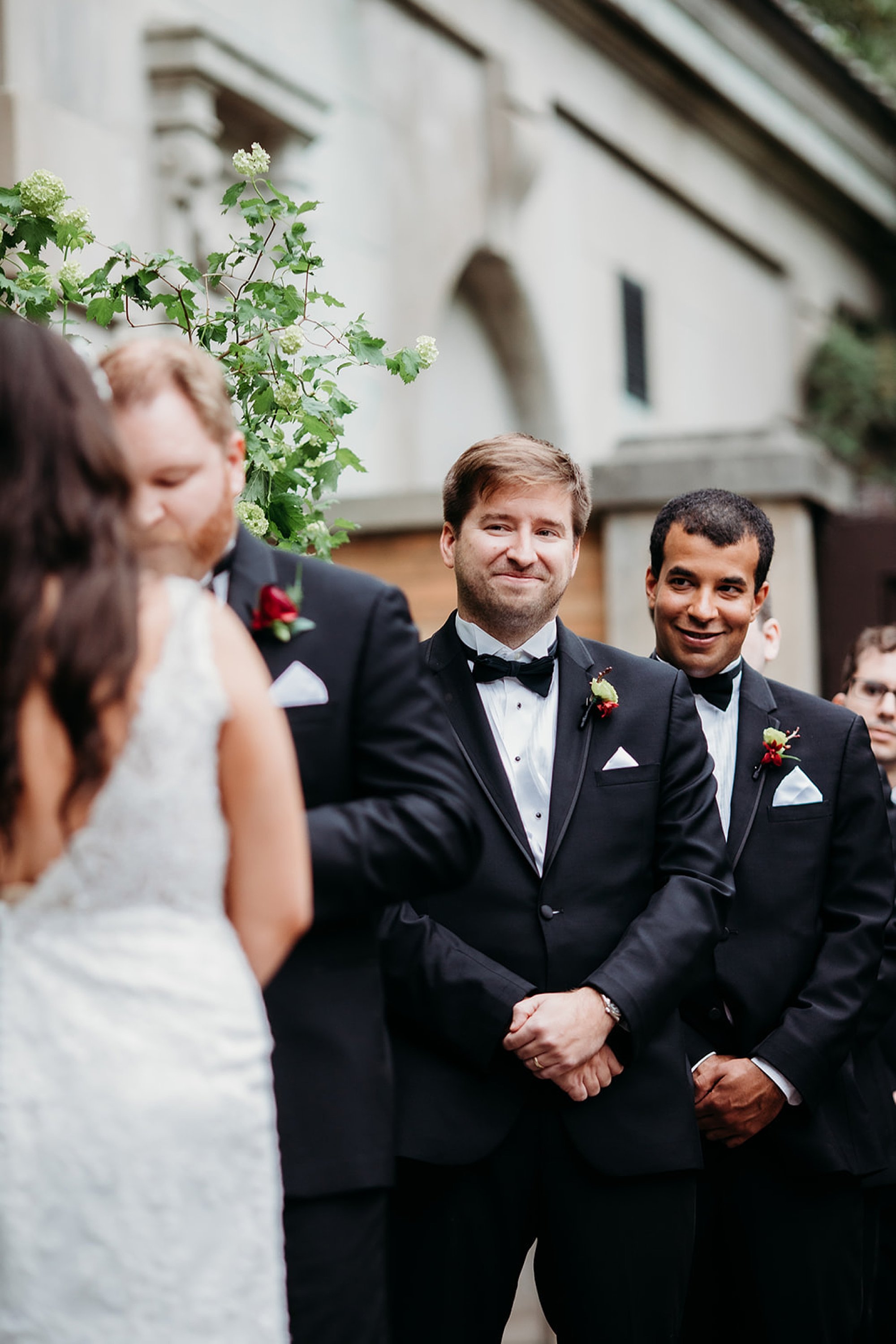 best man smiles at couple during wedding ceremony outside the Elephant House at the Bronx Zoo