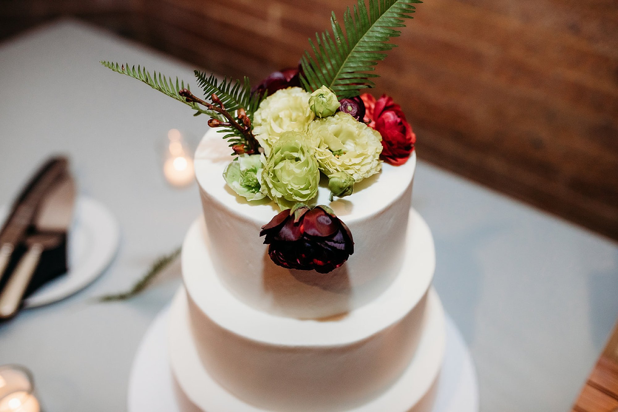 wedding cake with green and red flowers on top