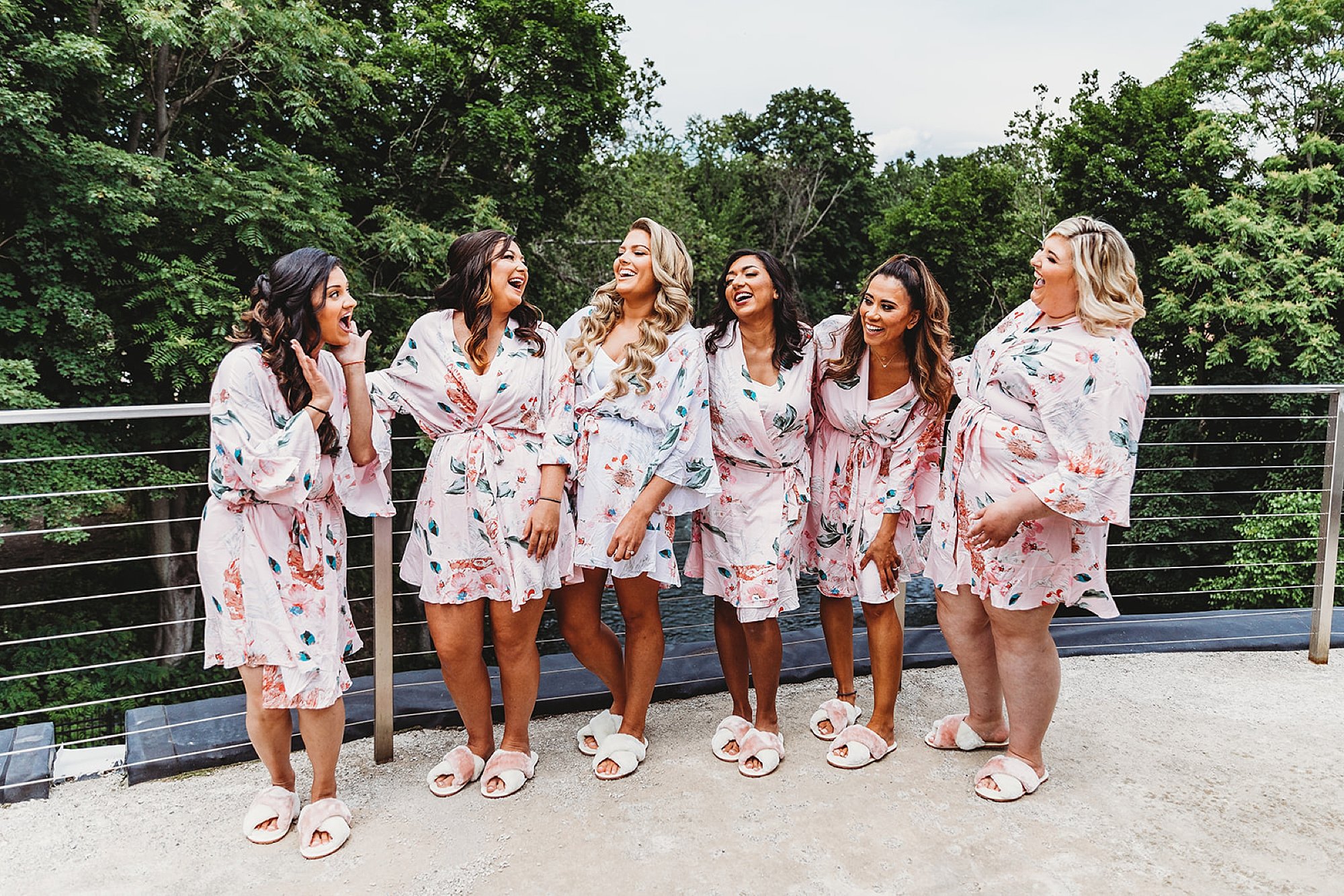 bride stands with bridesmaids on balcony at the Roundhouse in matching floral pajamas 