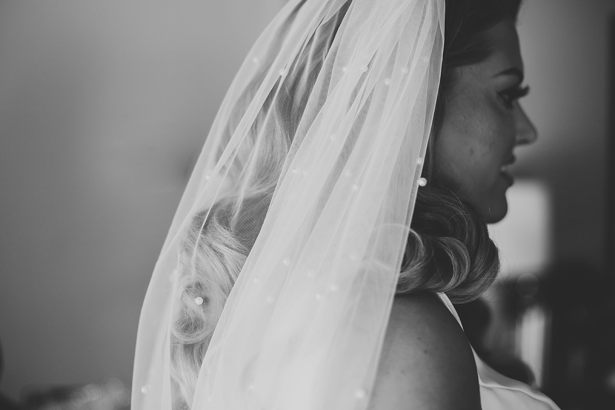 black and white portrait of bride with veil behind her