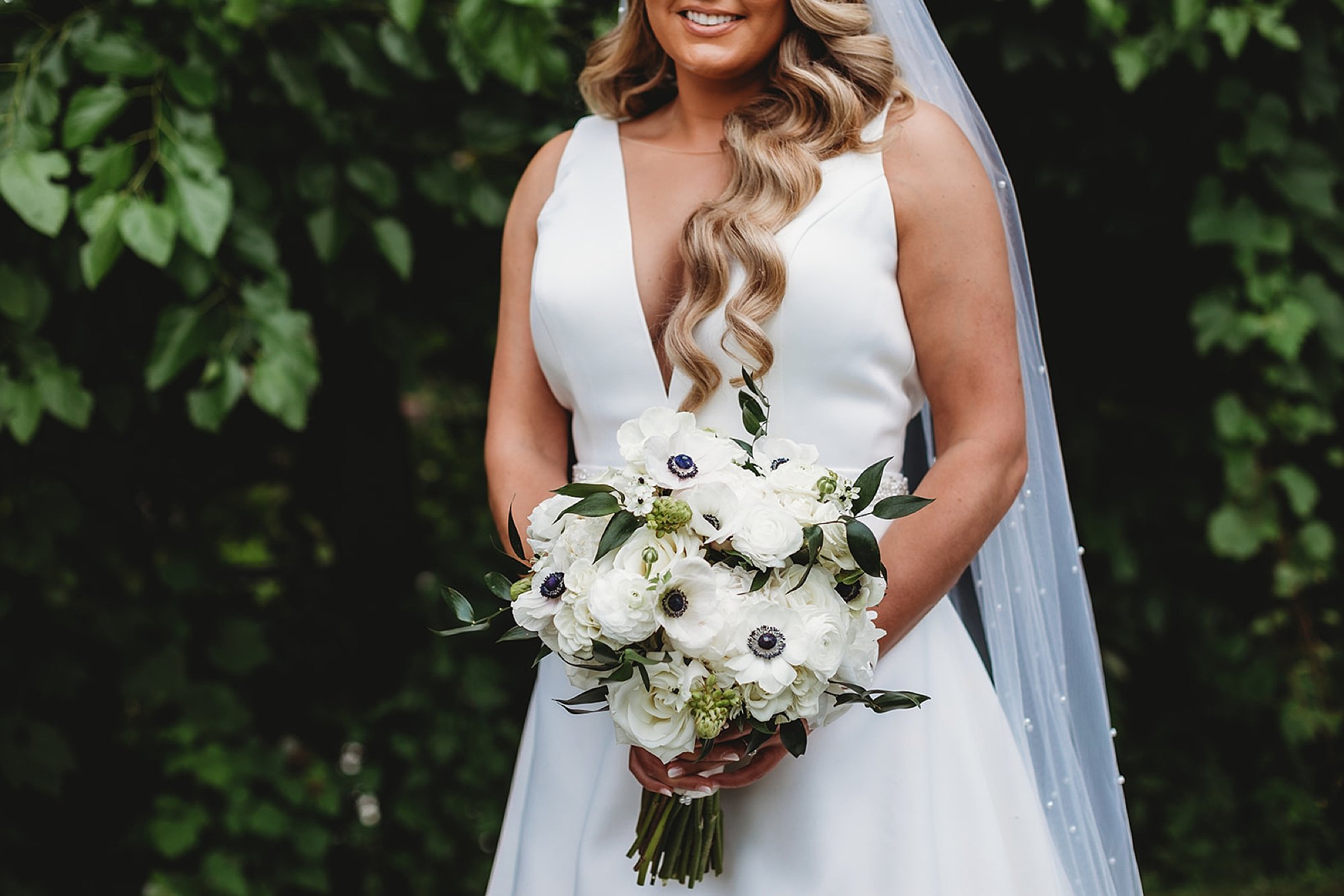 bride holds bouquet f white flowers in v-neck dress