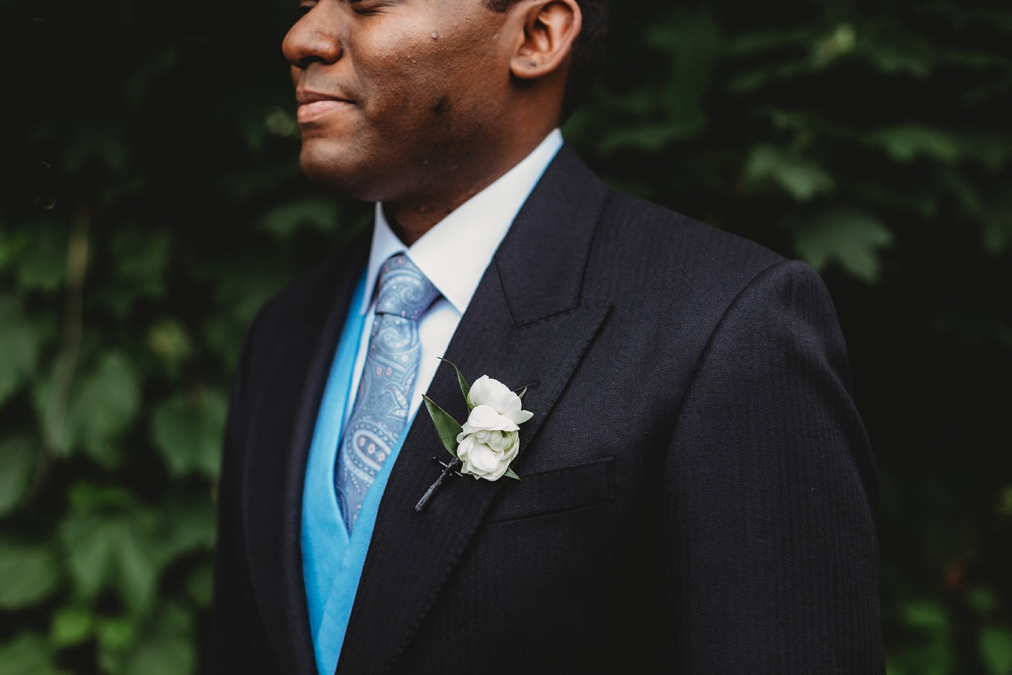 groom smiles in English morning suite with light blue tie and vest 
