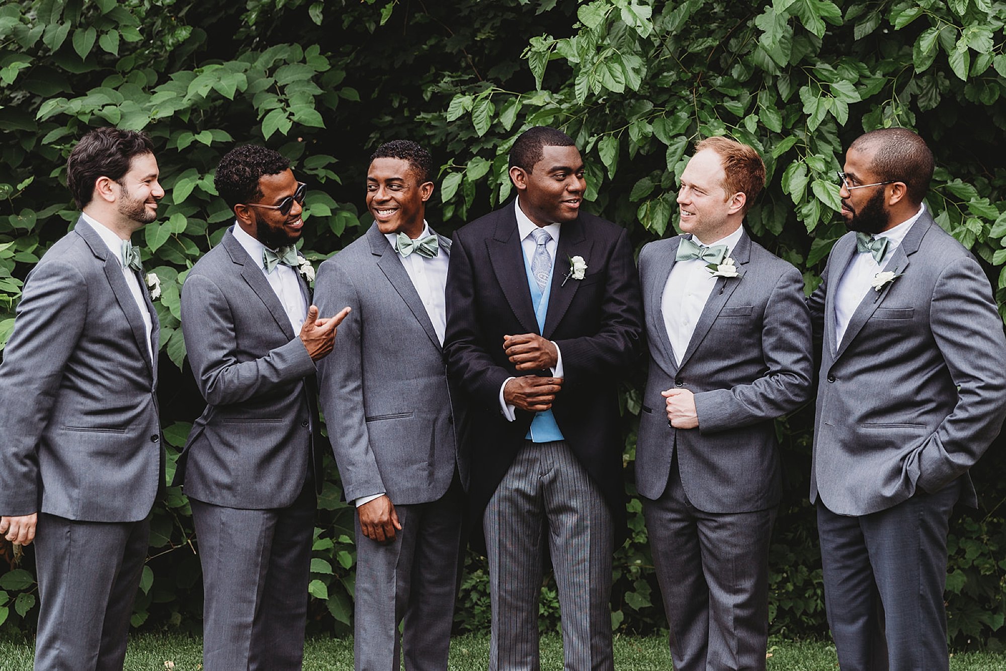 groom laughs with groomsmen in grey suits at The Roadhouse