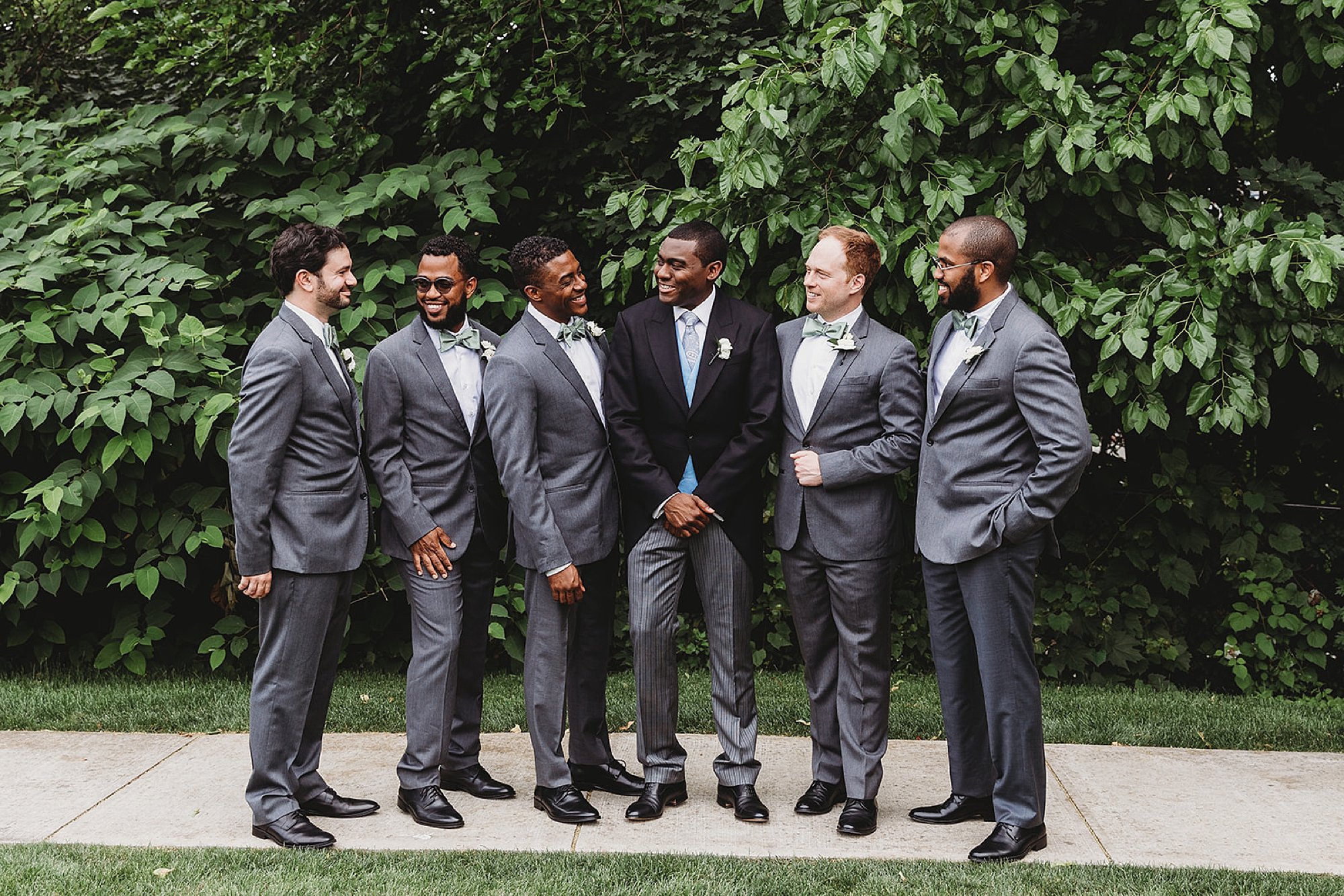groom stands with groomsmen in grey suits at The Roadhouse