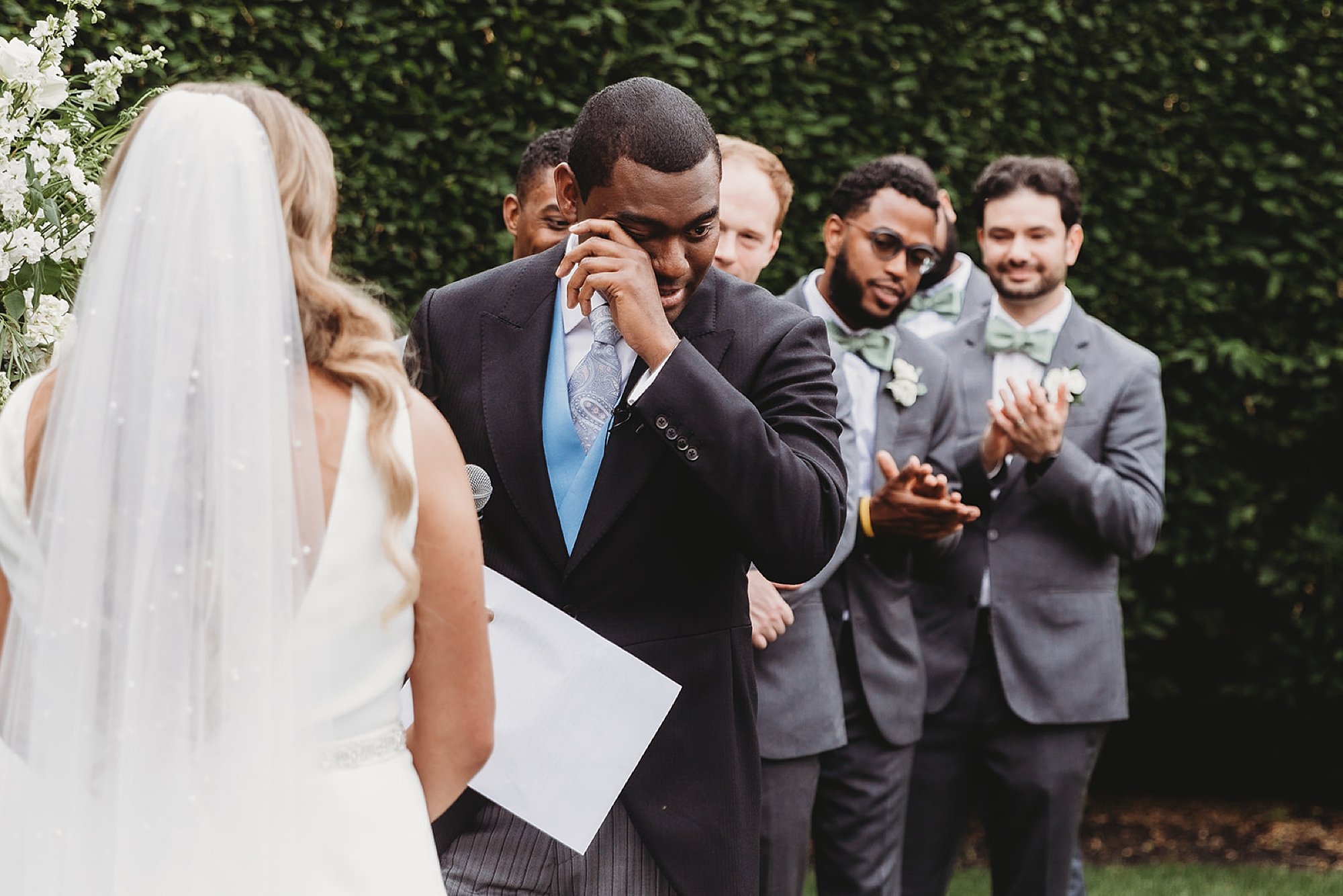 groom wipes away tear during wedding ceremony in gardens at The Roadhouse in Beacon NY