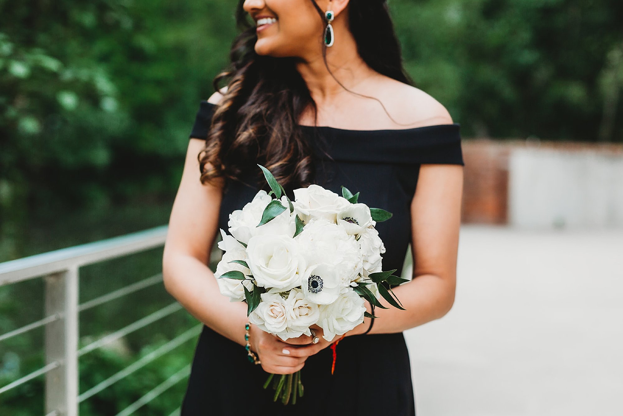 bridesmaid in black gown holds bouquet of white flowers 