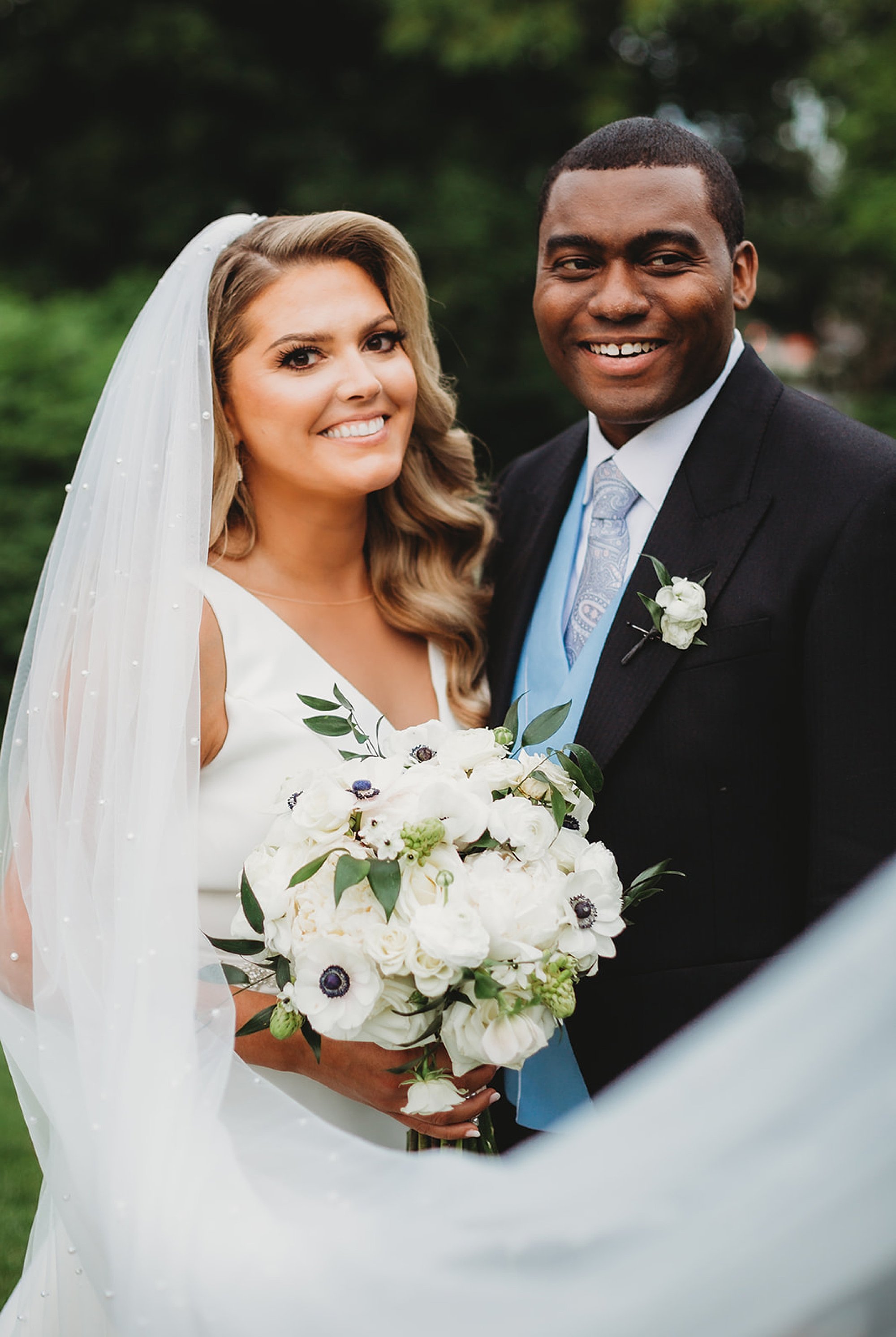 newlyweds smile with bride's veil around them