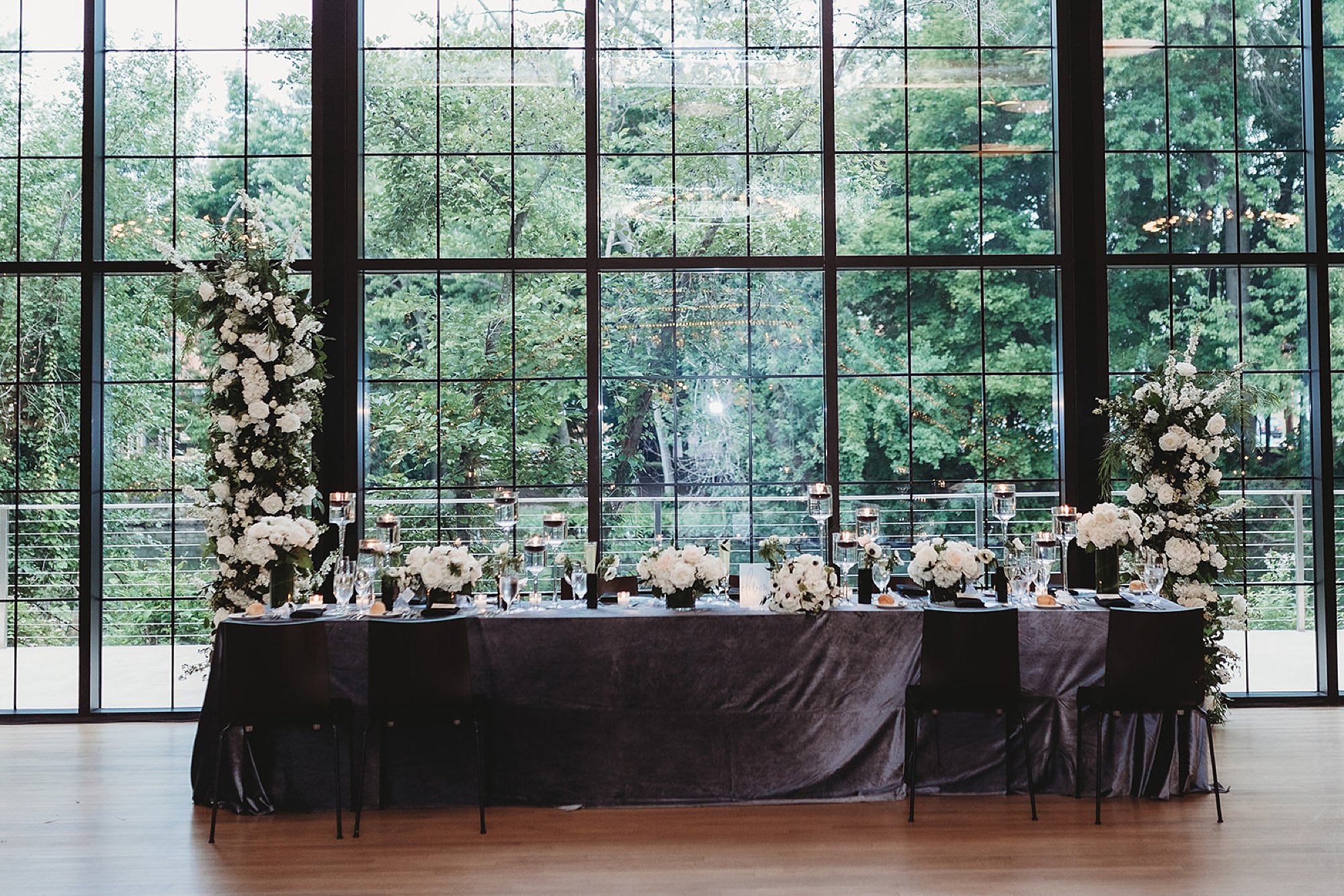 head table by window with tall floral installations at side