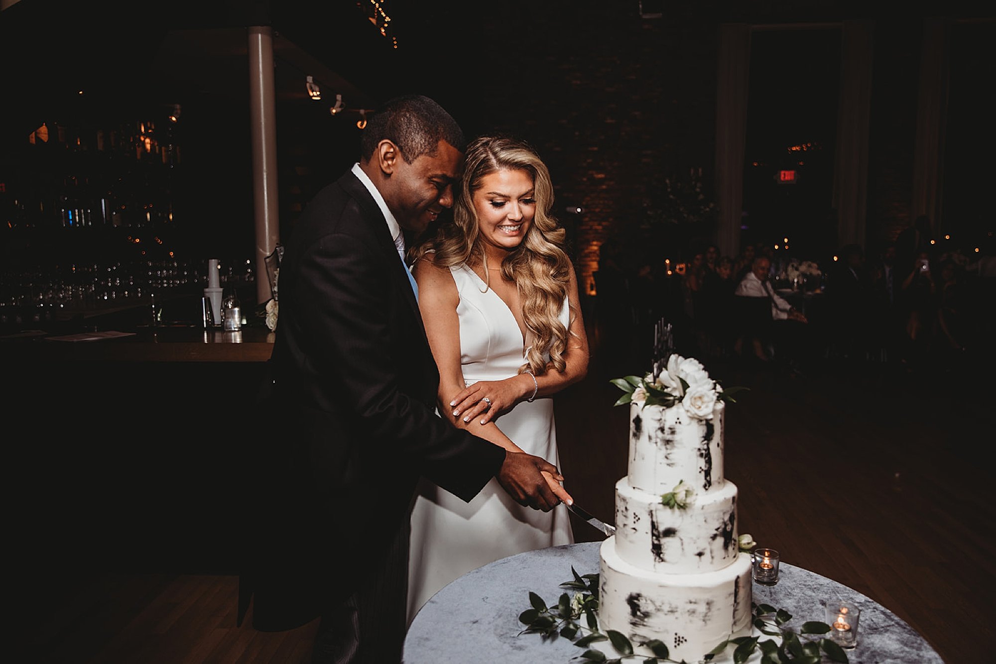 newlyweds kiss wedding cake together at Beacon NY wedding reception