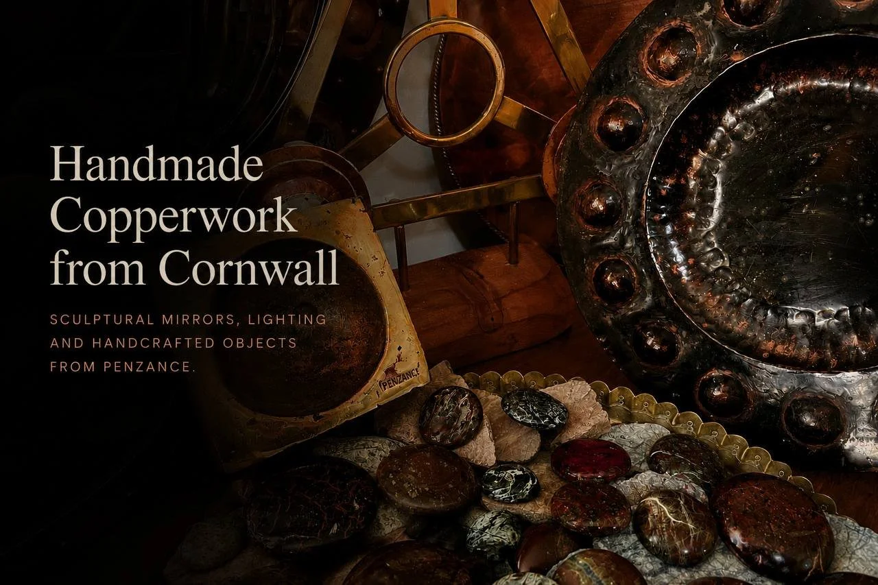 A display of handcrafted copper sculptures, mirrors, lighting fixtures, and decorative objects from Penzance, Cornwall. The items include copper bowls, reflective surfaces, and jewelry with a rustic, artistic style.