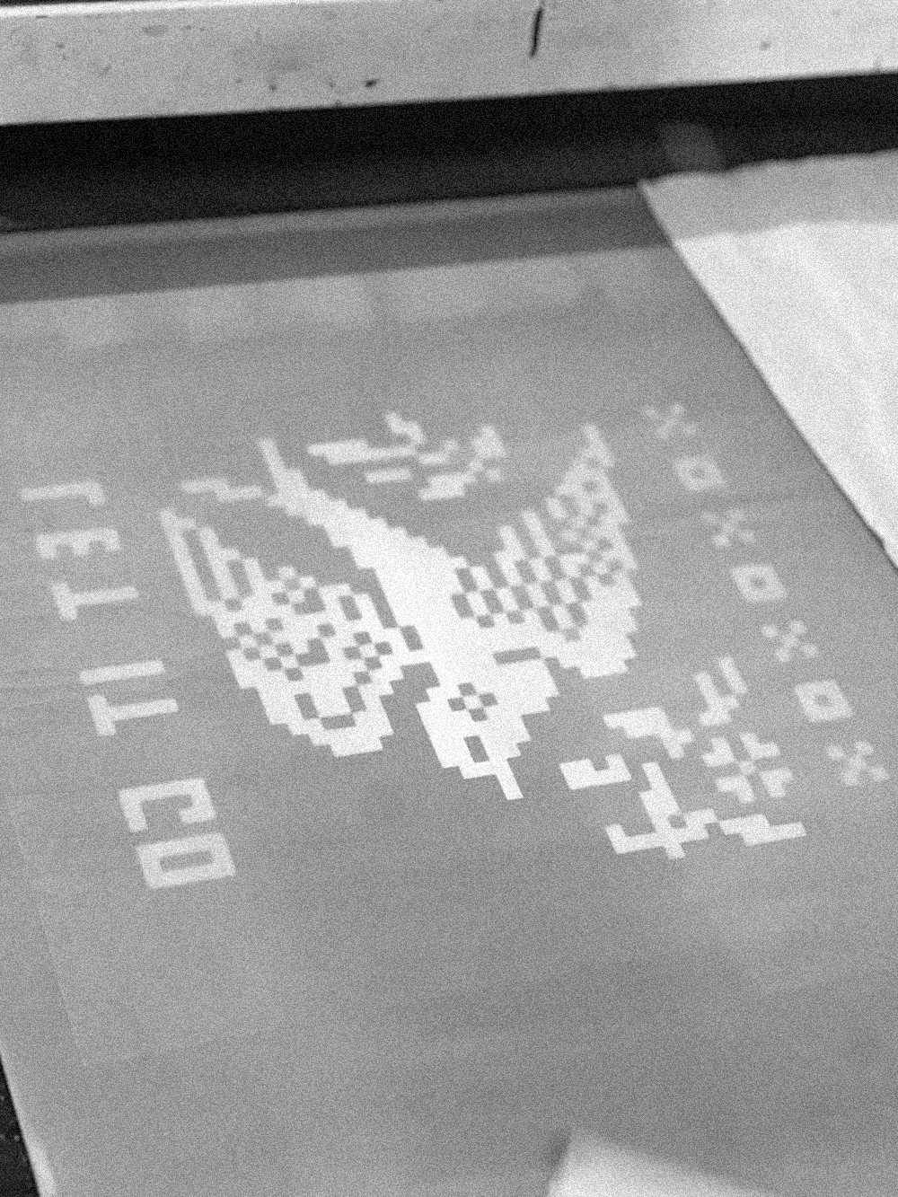 A printed pixel art design of a dove on a printing screen