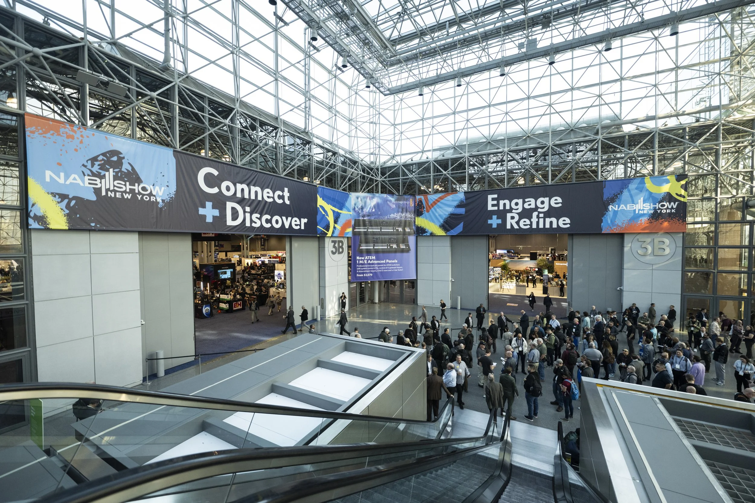 Crowd in large convention center at NAB Show New York, with banners displaying the slogans "Connect + Discover" and "Engage + Refine."
