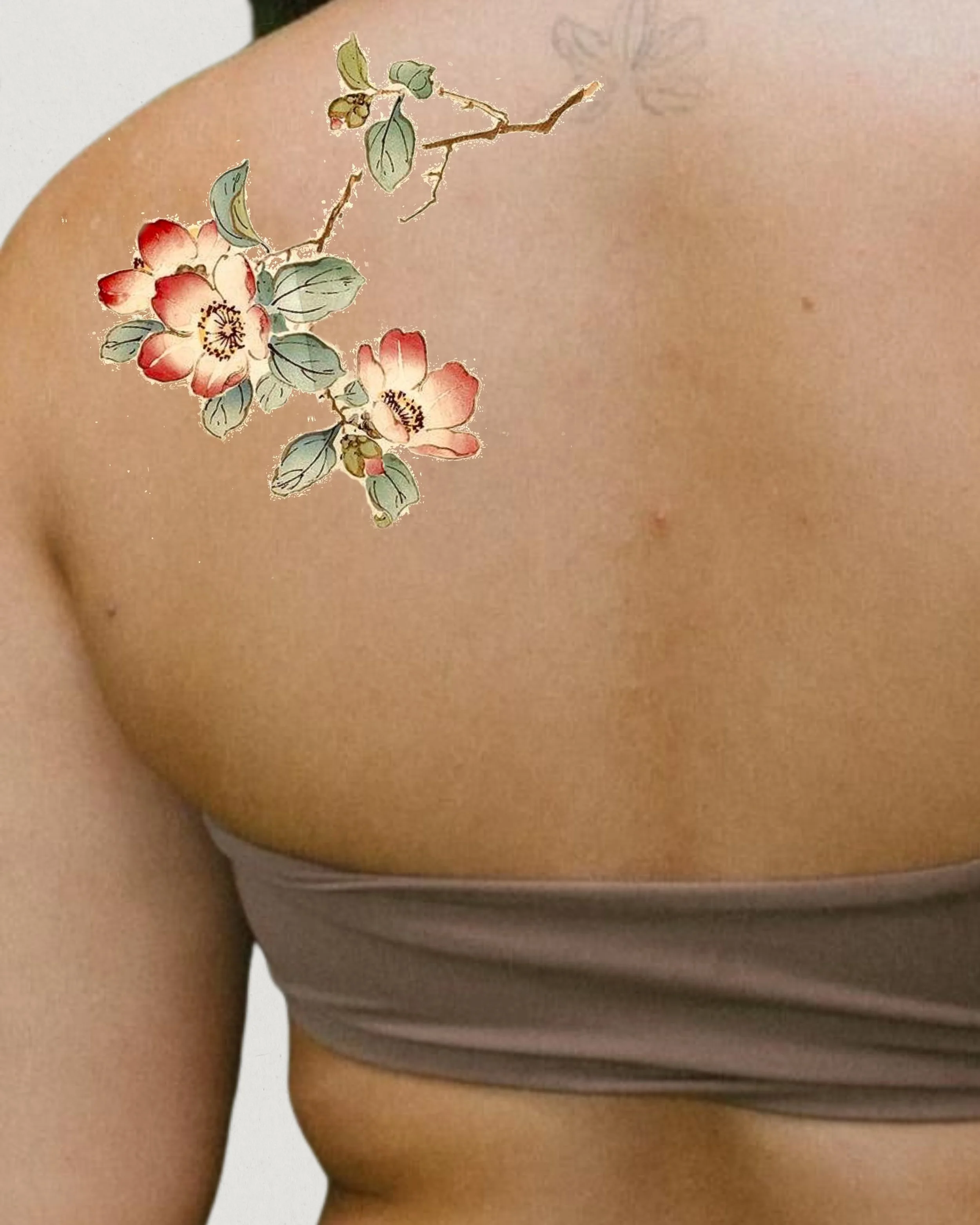 A tattoo of pink and white flowers with green leaves and branches on a person's upper arm and shoulder.