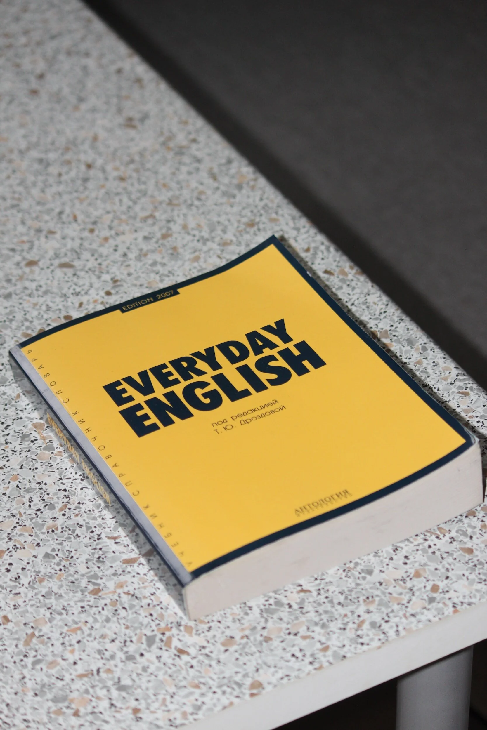 Yellow book titled 'Everyday English' on a speckled surface.