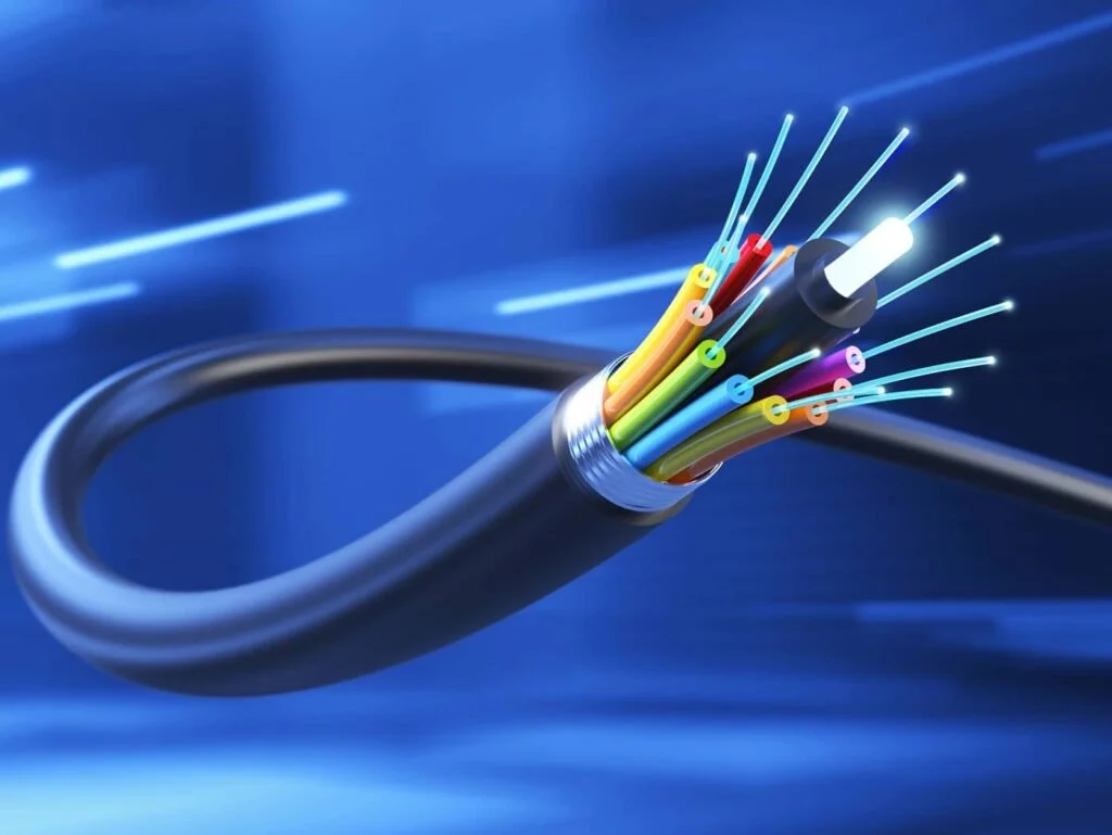 Close-up of a cut fiber optic cable with colorful fibers inside, with a blue background and light streaks.