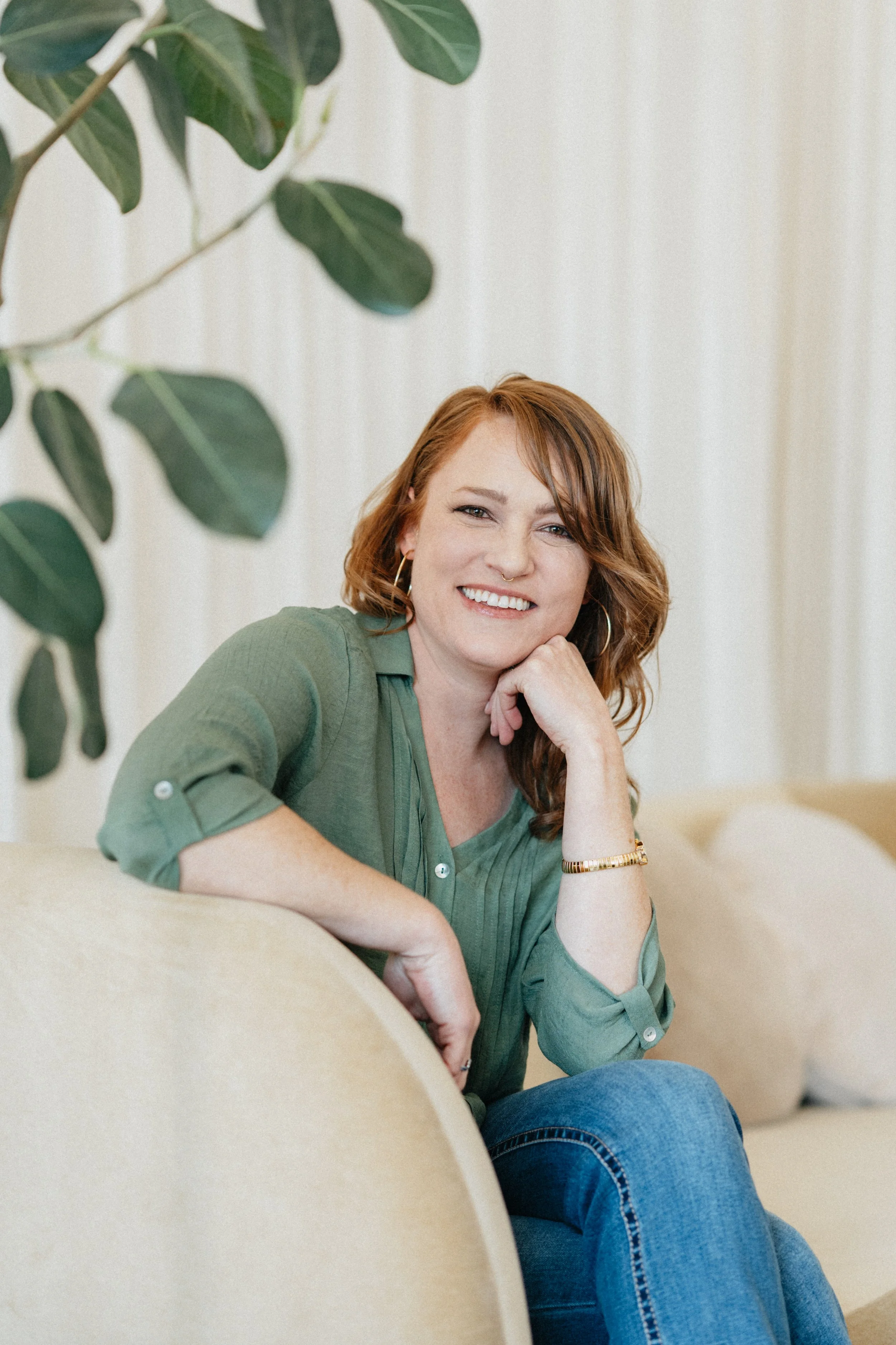A woman sitting with a green shirt and red hair
