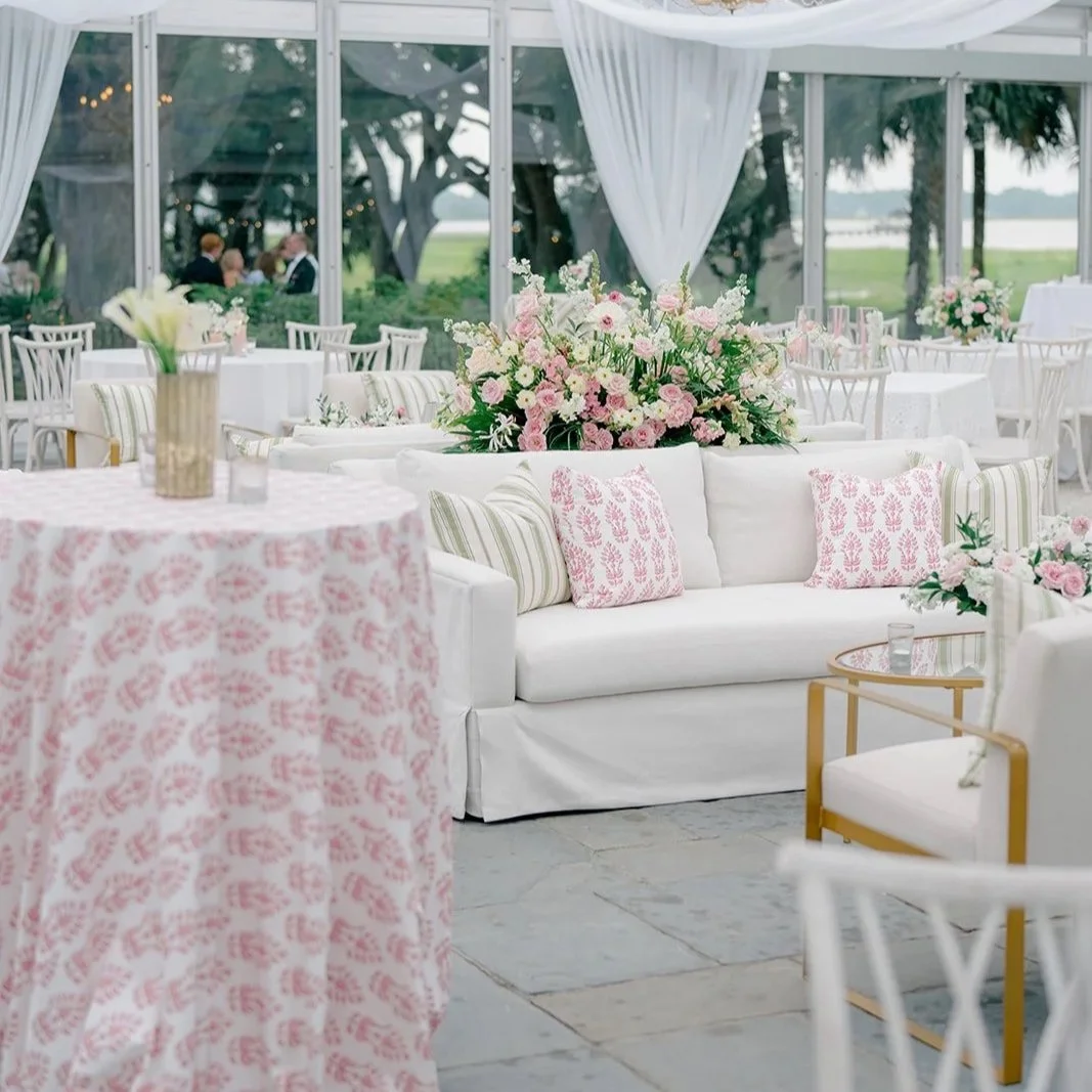 Elegant tented wedding reception with white linen furniture, pink and white flowers and linens.